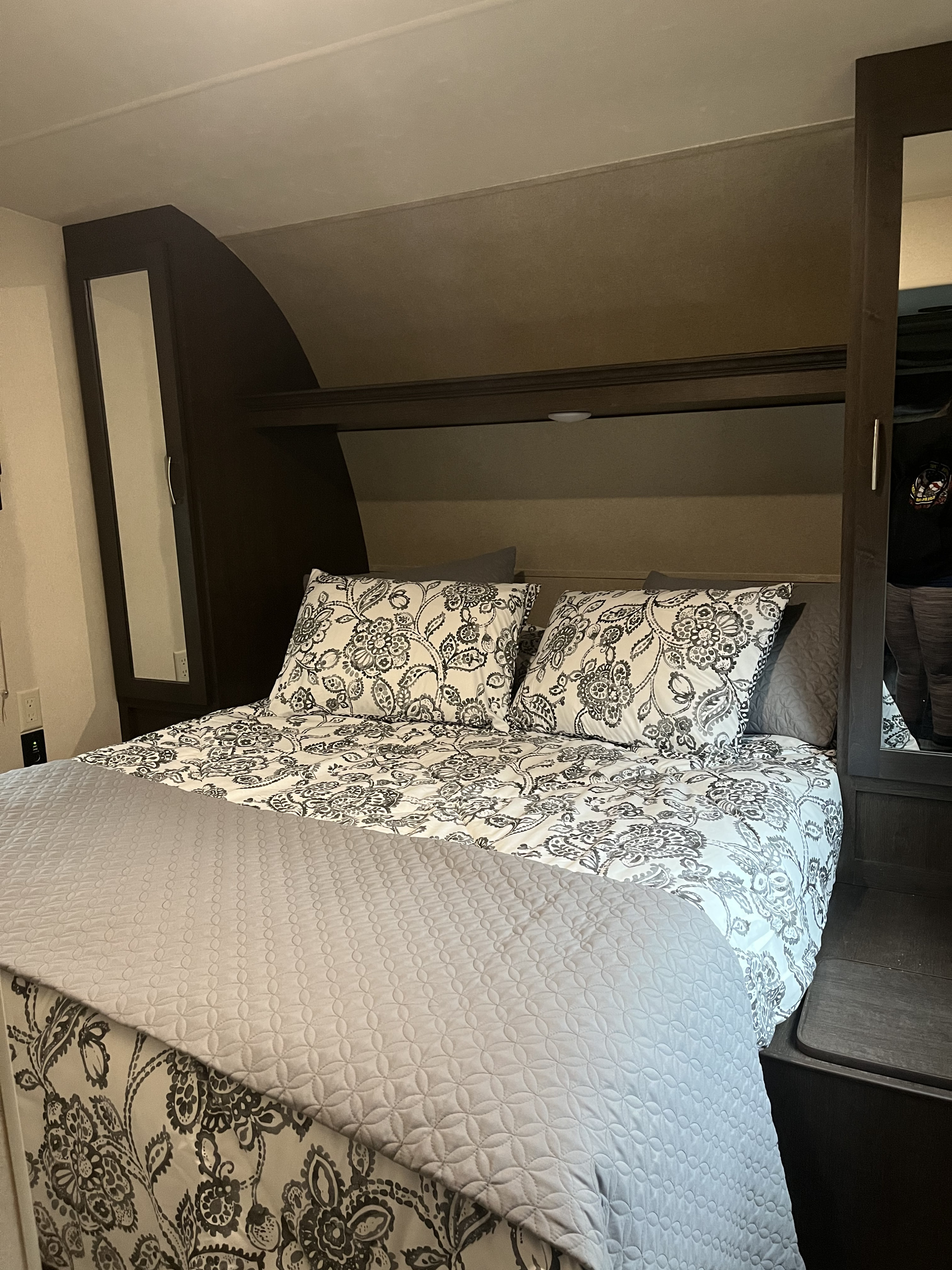 RV rental bedroom: comfy bed with floral bedding & smart built-in storage.. Forest River Stealth 2017