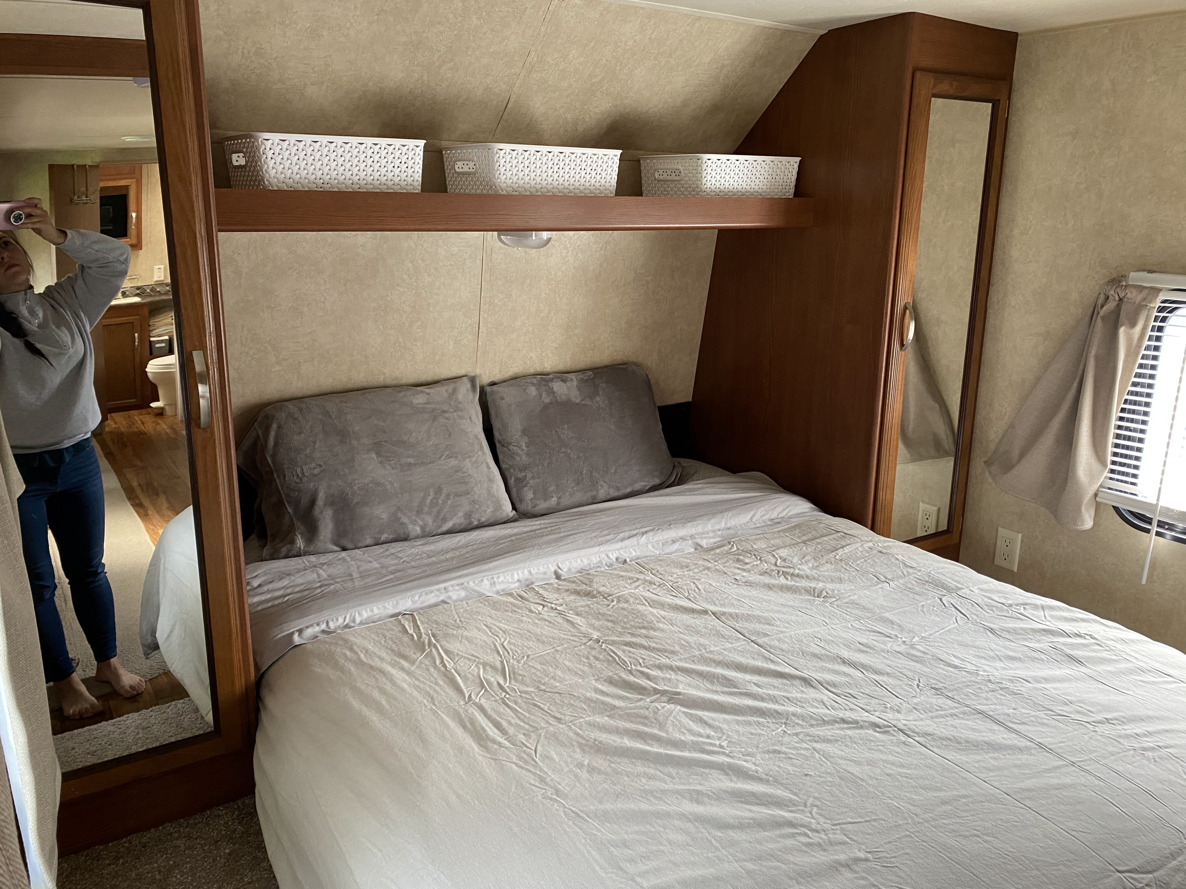 RV rental bedroom: cozy bed, overhead storage, mirrored closet reflecting a person in a compact space.. Forest River Salem 2015