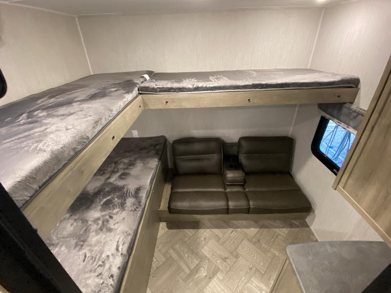RV rental interior: Stacked bunks and sofa offer multiple sleeping areas. Light wood-look floor.. Forest River Palomino Puma 2022
