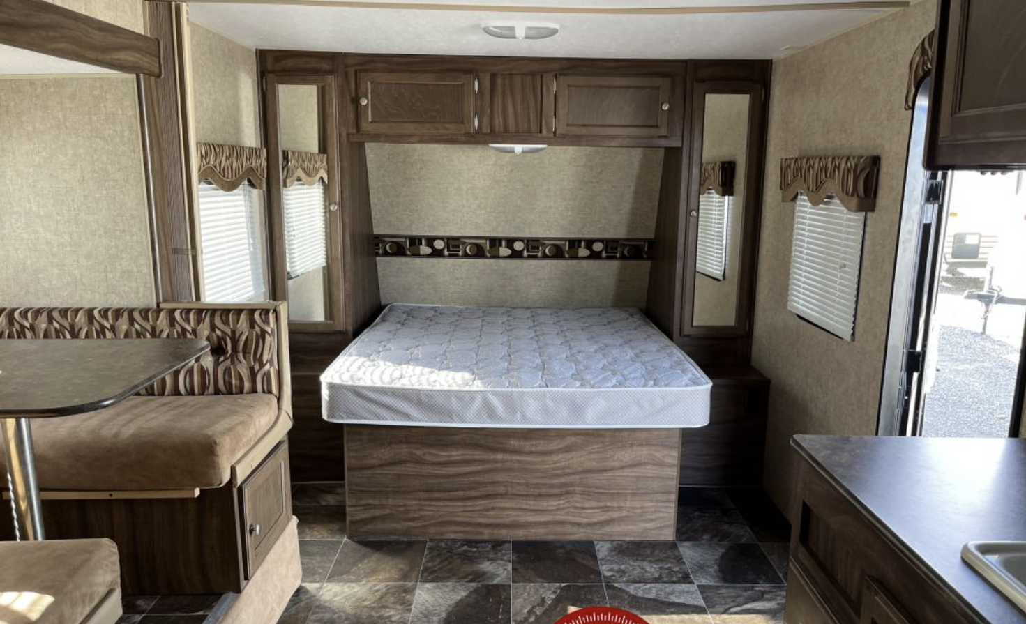 Inside this RV rental: Features a compact bed area with overhead cabinets, a dining booth, and a partial kitchen counter.. Sportsmen Show Stopper 2016
