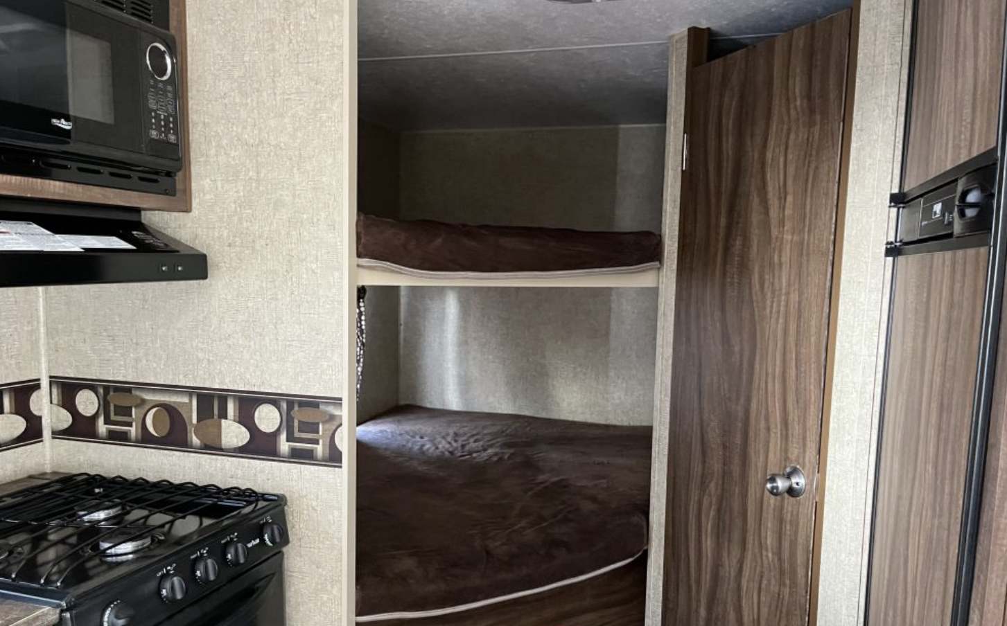 This RV rental interior features a compact kitchen with microwave, stove, and comfortable built-in bunk beds.. Sportsmen Show Stopper 2016