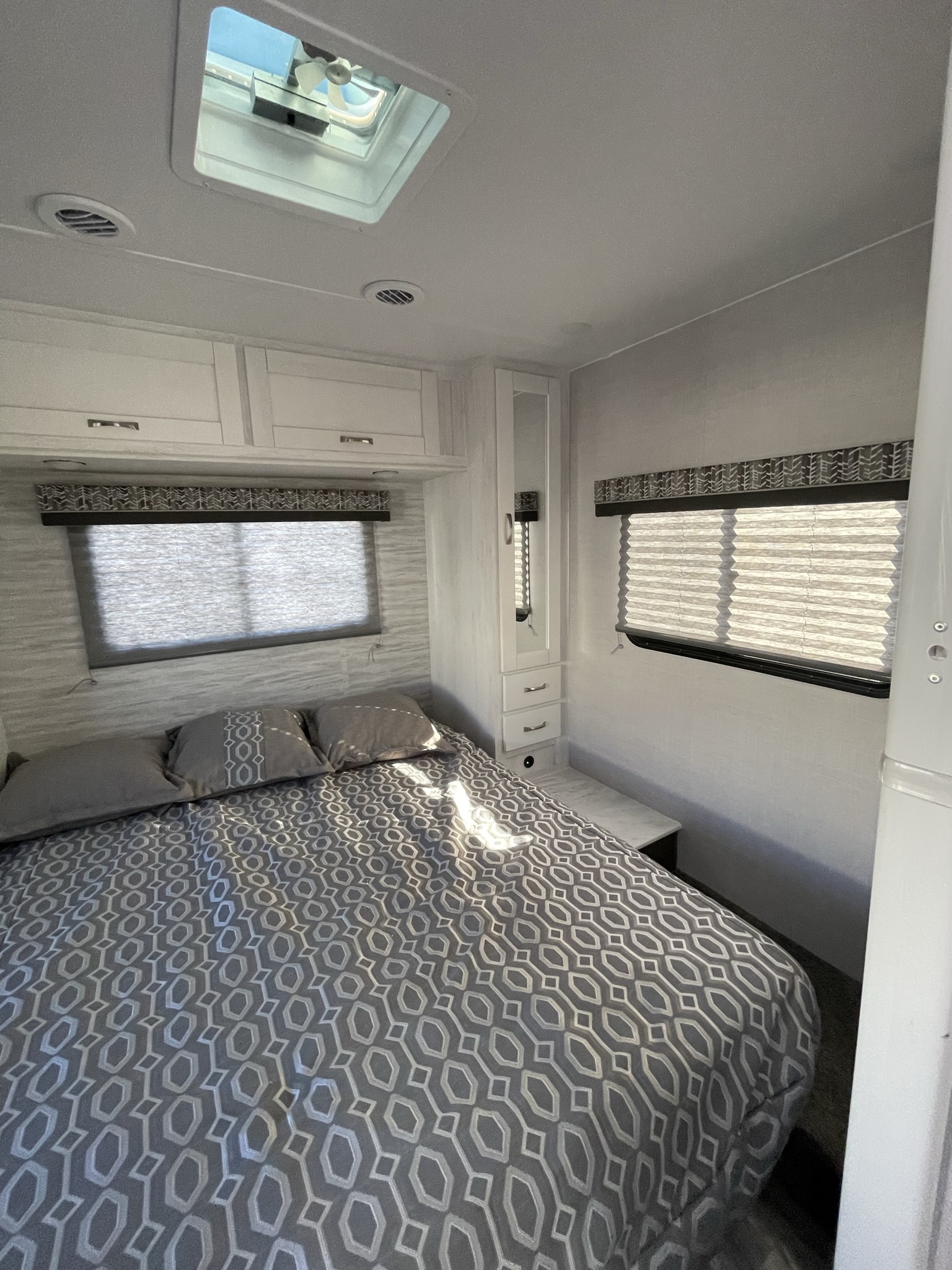 Cozy RV rental bedroom with patterned bedding, overhead cabinets, and a skylight for your travel adventures.. Gulf Stream Conquest 2022