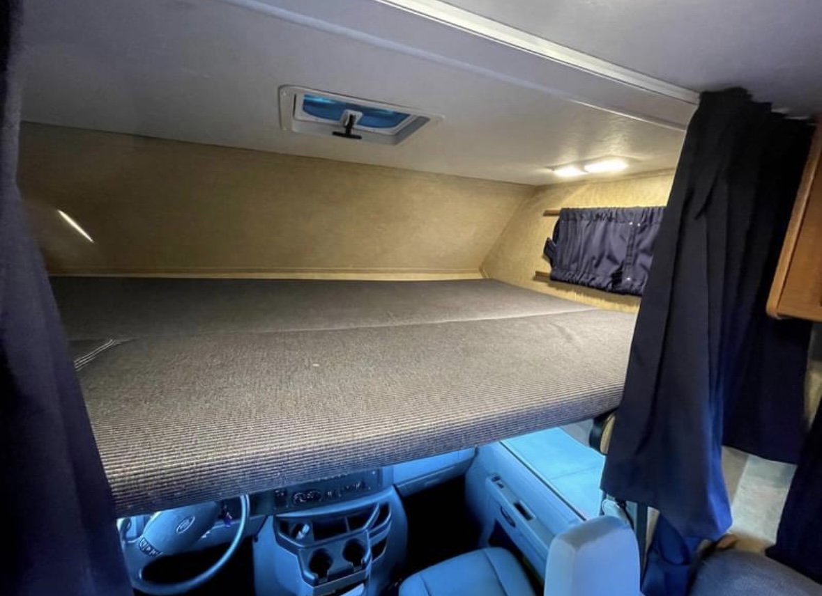 Spacious cab-over bunk bed in an RV rental, offering comfortable sleeping above the driver's area.. Thor Majestic 2016