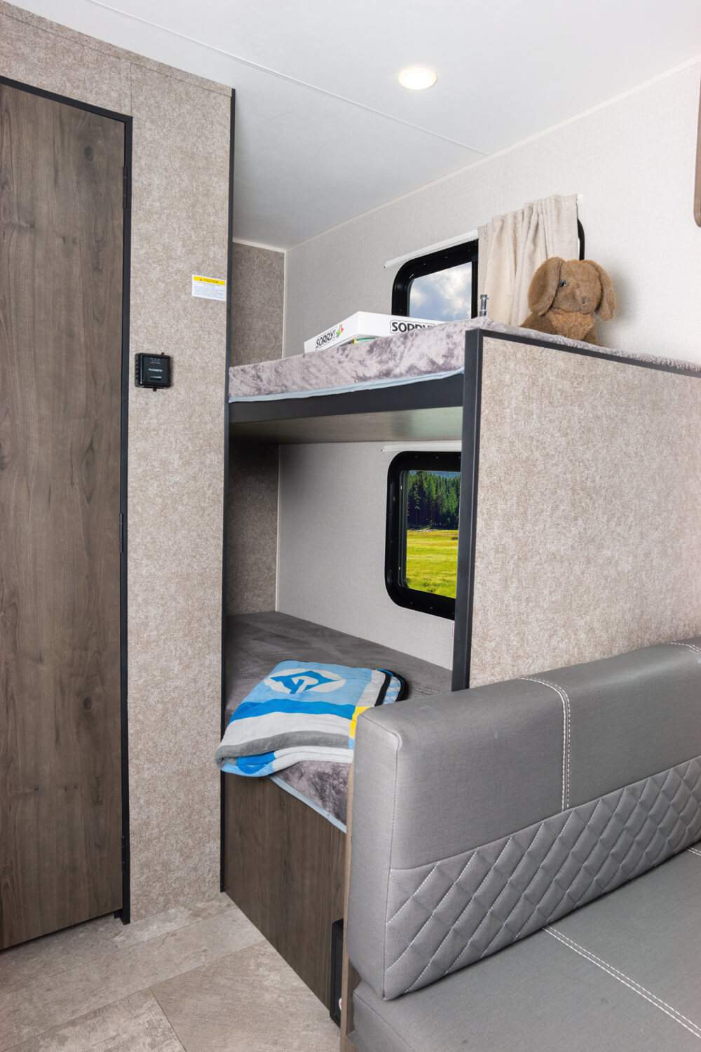 This rv rental's cozy interior features bunk beds, a sofa, and window views of nature, ideal for family trips.. Highland Ridge RV Open Range OT19BH 2021
