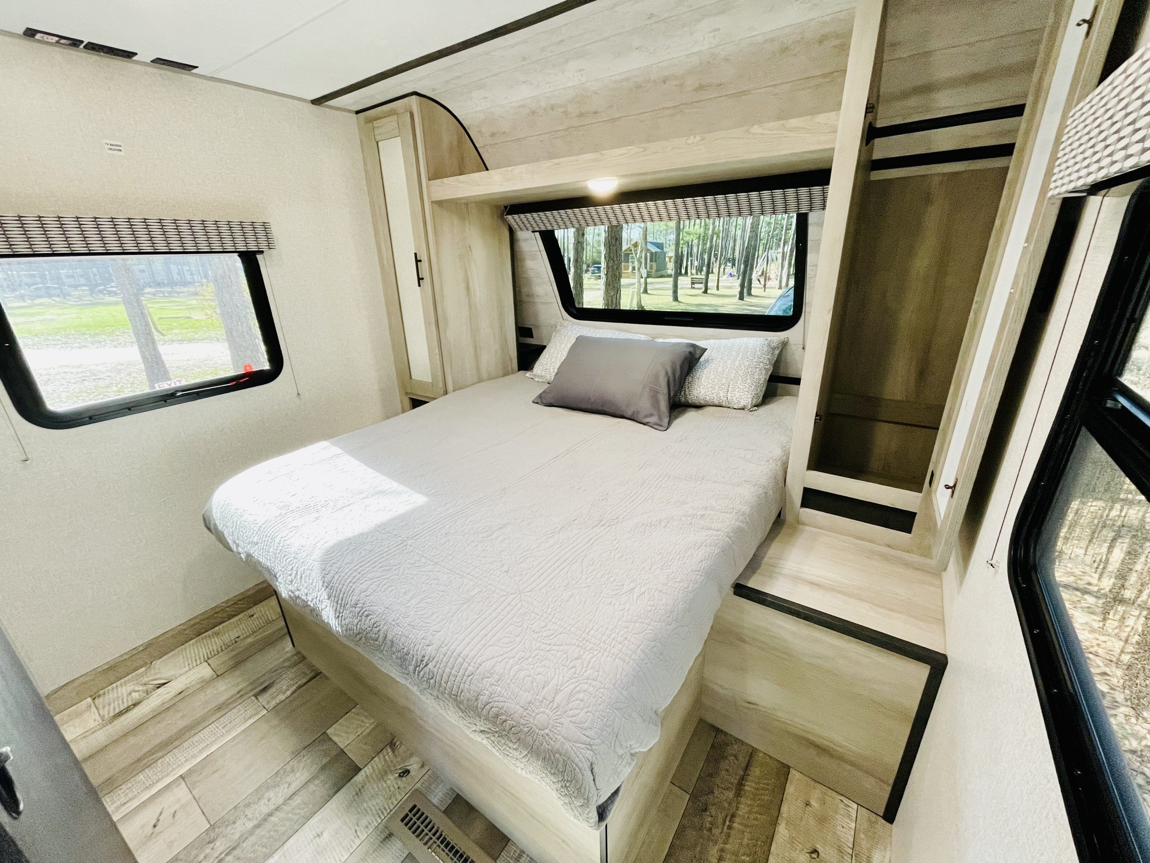 Cozy RV rental bedroom. Features a comfy bed, built-in storage, and large windows with outdoor views.. KZ Connect 2022