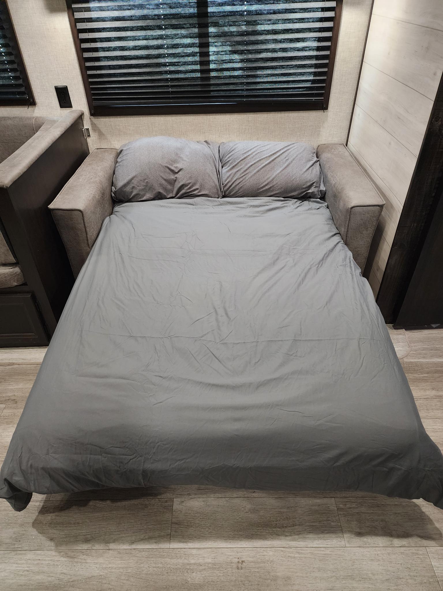 RV rental: Gray sofa bed converted to a cozy sleeping area, complete with pillows and bedding, in a compact interior.. Jayco Jay Flight 2022