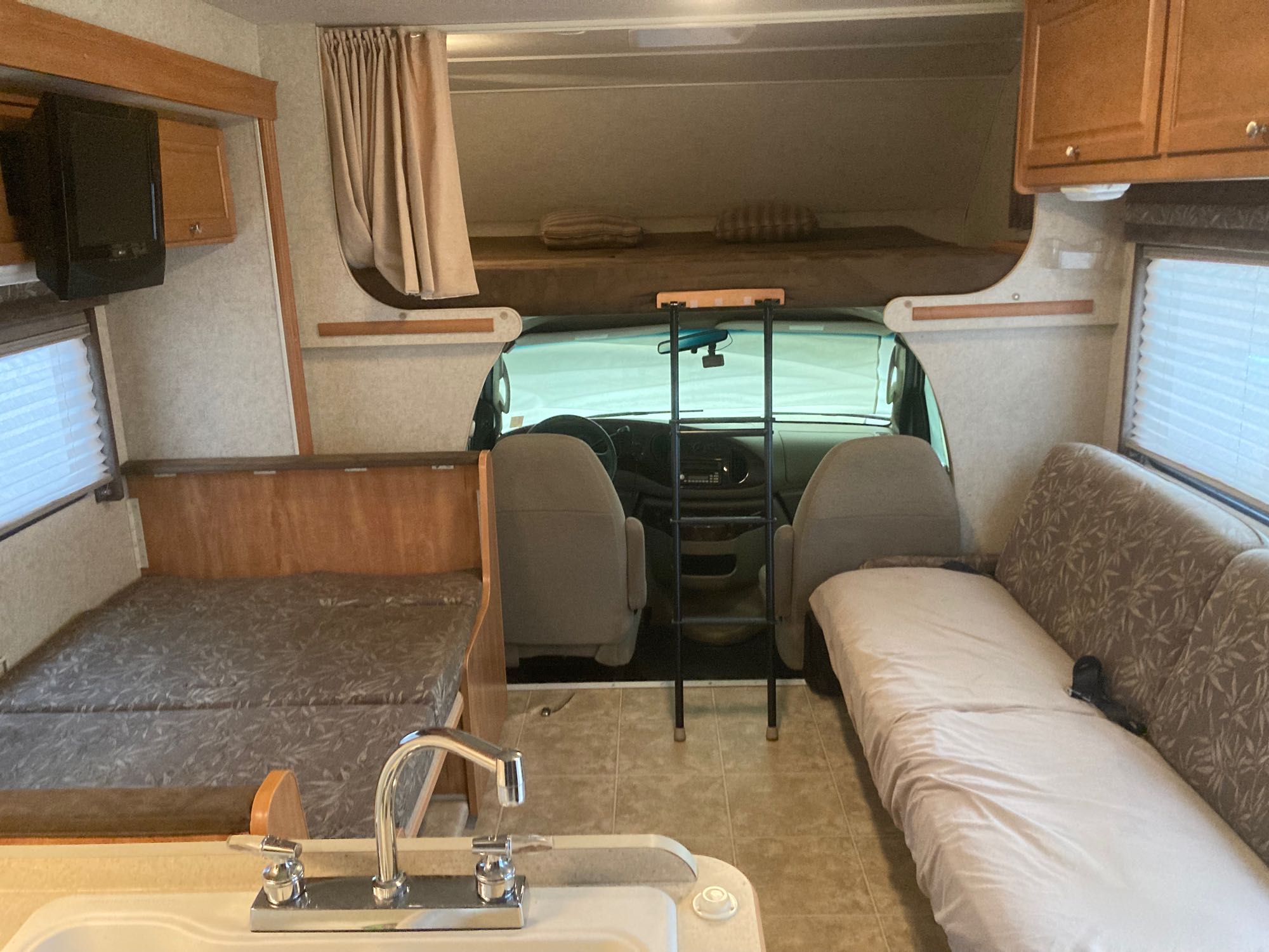 Spacious RV rental interior featuring a kitchen sink, dinette bed, sofa, and overhead bunk for comfortable travel.. Winnebago Chalet 2009