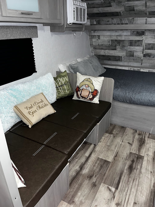Cozy RV rental interior with a dinette, bed, and modern wood-look finishes. Perfect for your next adventure!. Dutchmen Coleman Lantern LT 2023