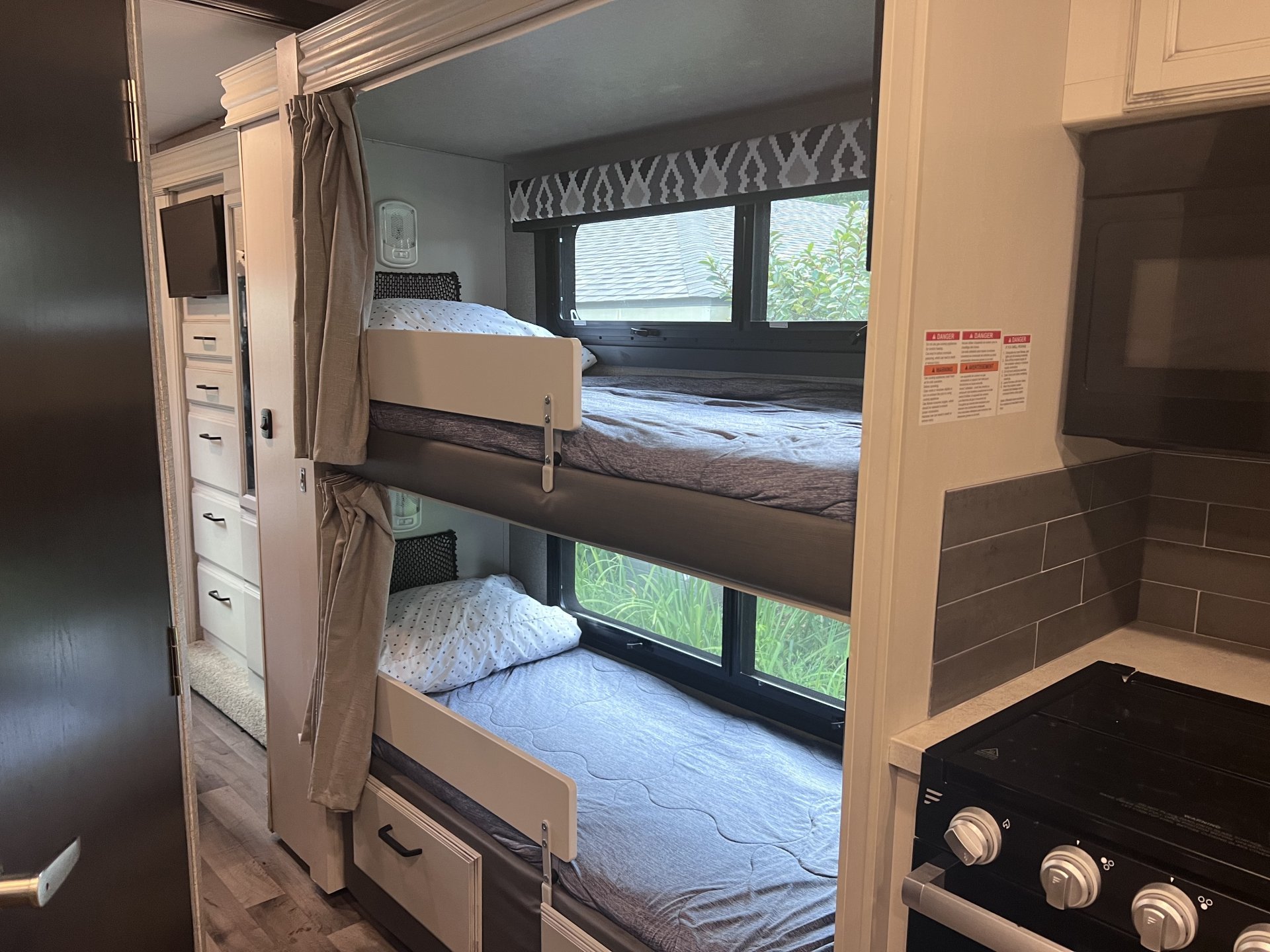 An RV rental's interior boasts bunk beds with outdoor views, a functional kitchen, and smart storage, perfect for family trips.. Jayco Greyhawk 2021
