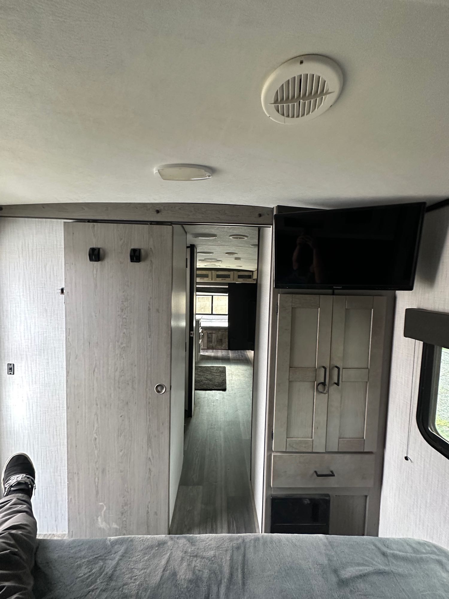 RV rental interior: View from bed shows light wood cabinets, wall-mounted TV, sliding door, and hallway.. Heartland Other 2021