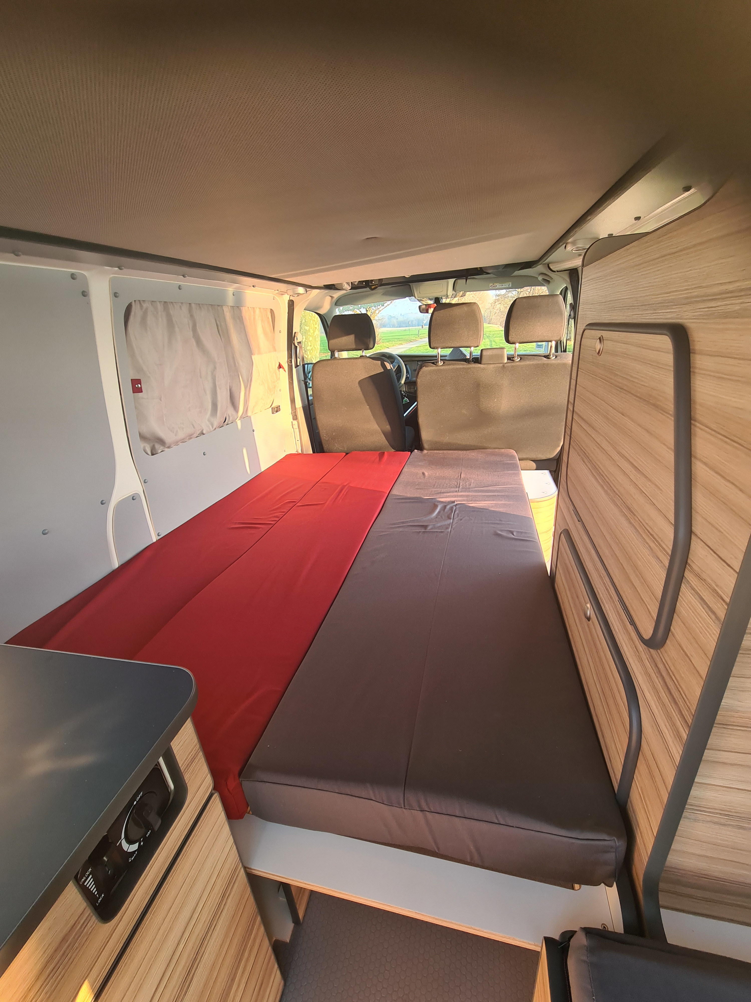 RV rental interior: View of the comfy bed and custom cabinetry in a well-equipped camper van, looking toward the front.. Volkswagen Transporter 2021