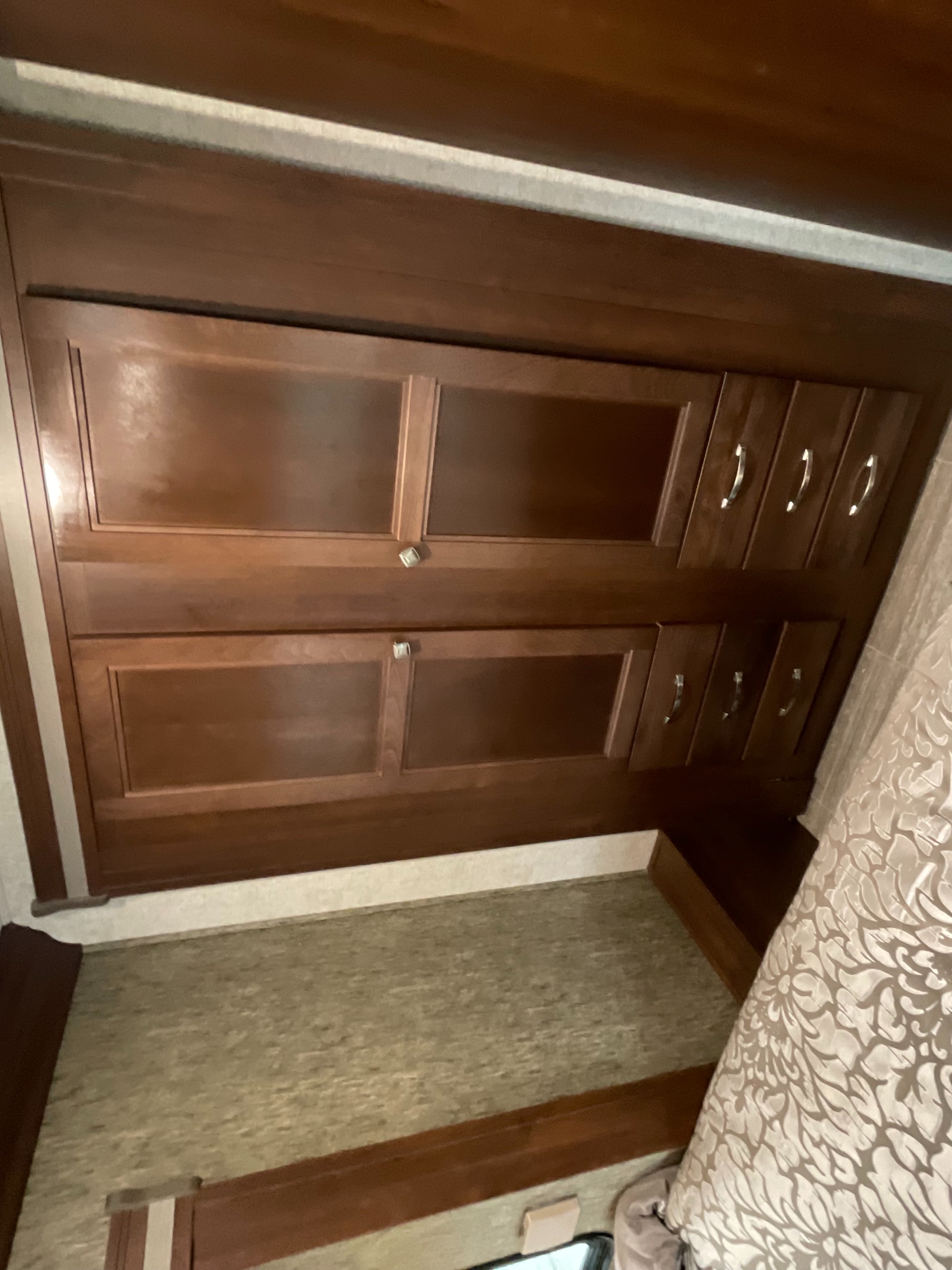 RV rental bedroom with wooden cabinets, drawers, and a bed, offering practical storage and comfort.. Forest River Sunseeker TS 2020