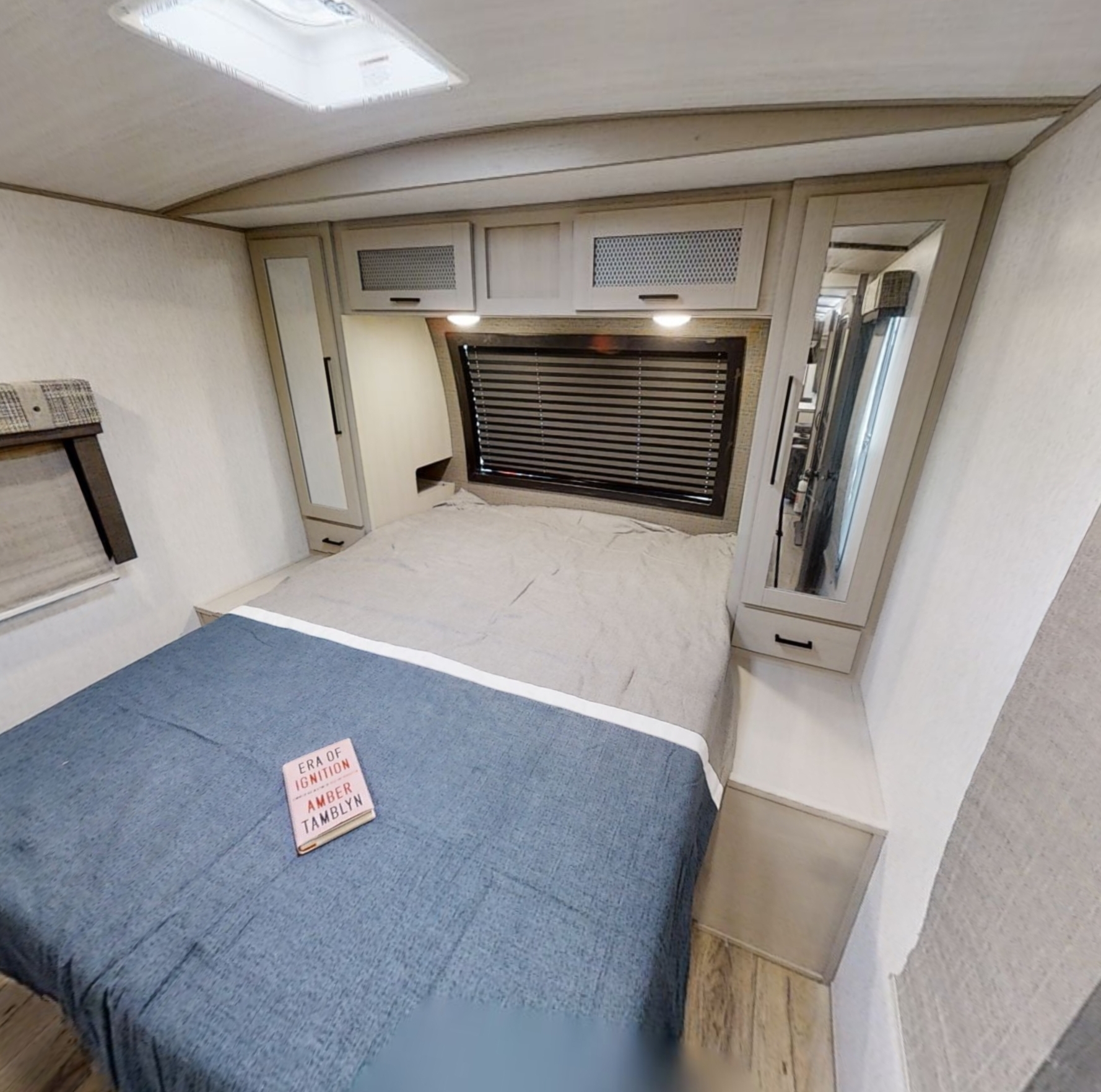 RV rental bedroom with bed, overhead cabinets, skylight, and mirrored storage.. Forest River Heritage Glen 2022