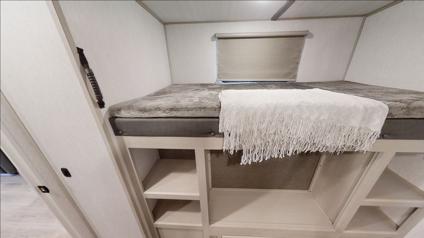 Cozy RV rental bunk bed with soft bedding, built-in storage, and a window, ideal for comfortable travel.. Forest River Heritage Glen 2022