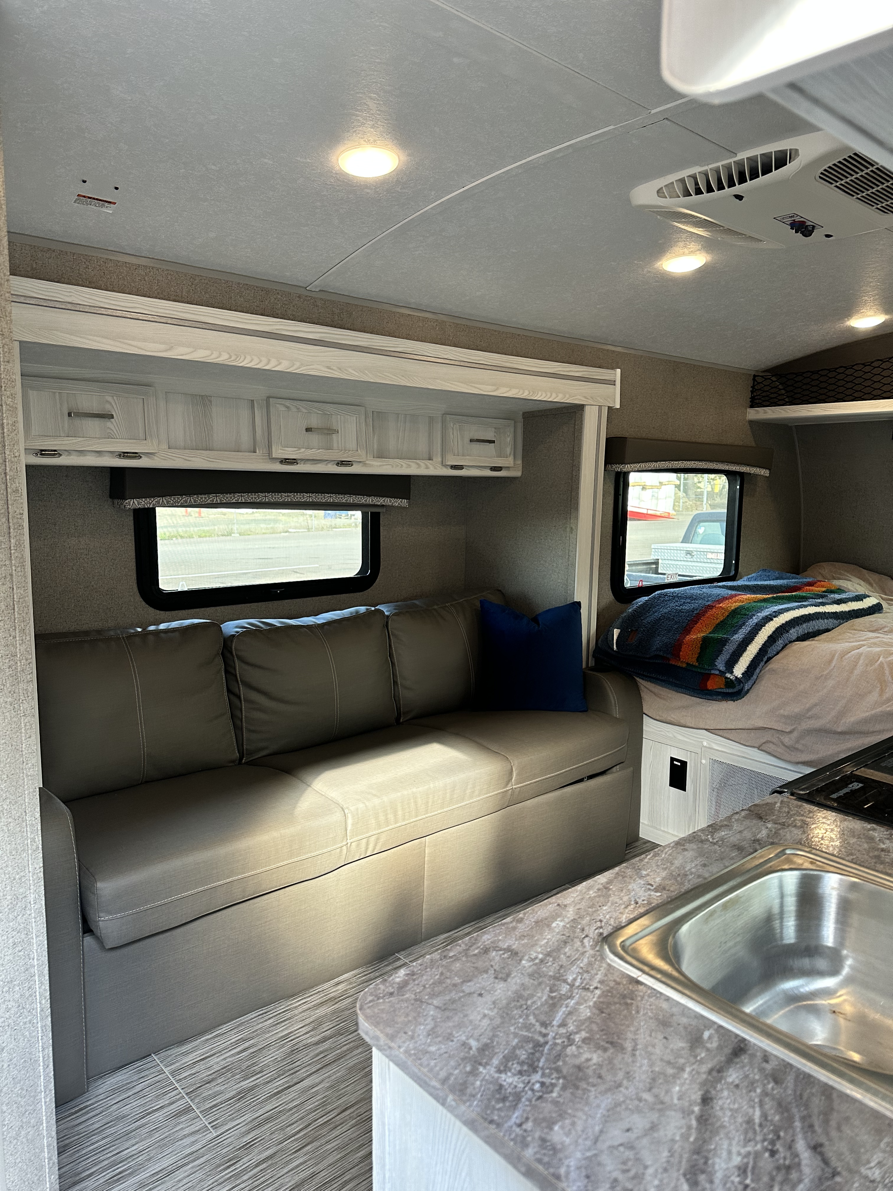 Cozy RV rental interior showcasing a sofa, comfortable bed, kitchen area with sink, and practical overhead storage.. Forest River Rockwood Geo Pro 2020