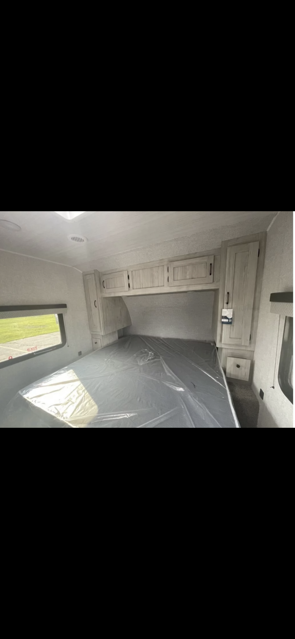 RV rental bedroom: Clean, bright interior showing a new bed, ample overhead cabinets, and window.. Forest River Della Terra 2022