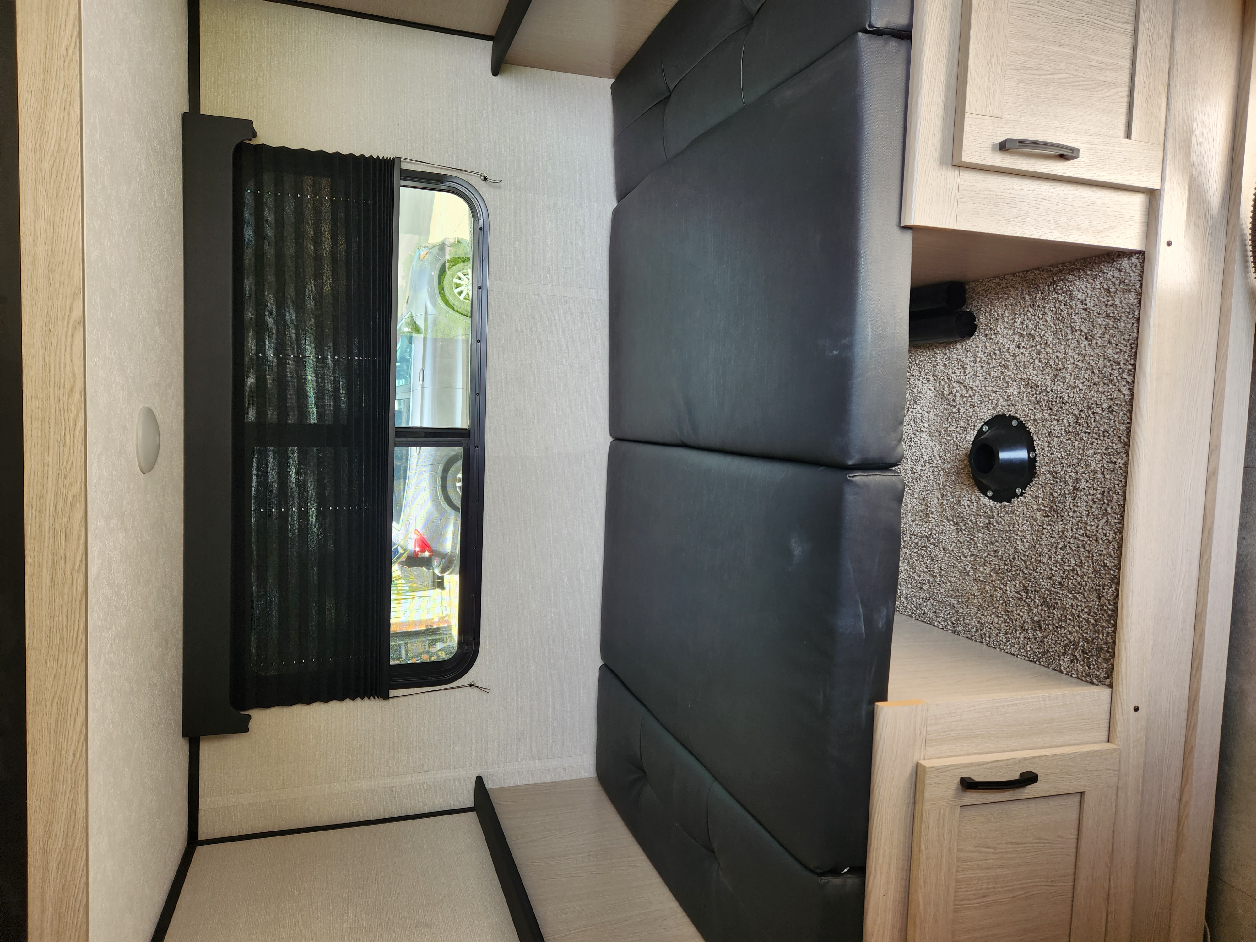 RV rental: Interior shot showing a black padded bench, window with blind, wood cabinetry, and a floor vent.. Coachmen Apex Nano 2021