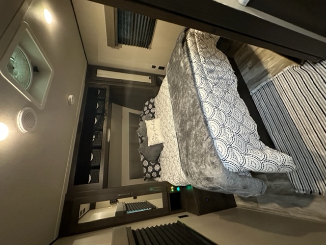 Modern RV rental bedroom: patterned bedding, plush throw, and built-in storage for travel comfort.. Grand Design Transcend Xplor 2021