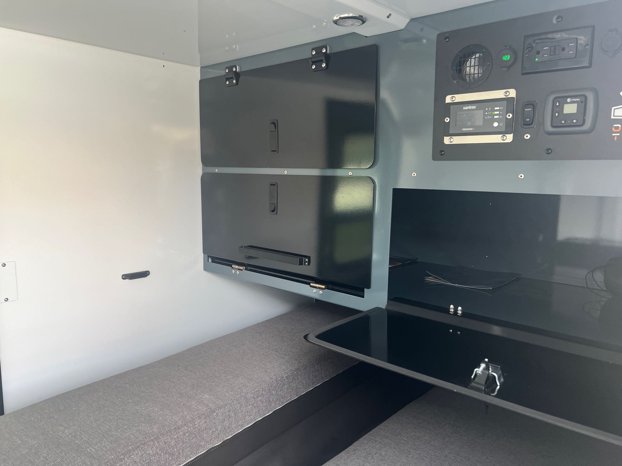 This RV rental interior features smart overhead storage, a detailed control panel, and a convenient pull-out table.. Off0Grid Explorer 2.0 2022