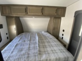 Inside an RV rental: a cozy bedroom with a queen bed, practical overhead cabinets, and side wardrobes. Ready for comfortable travels.. Forest River Vengeance 2022