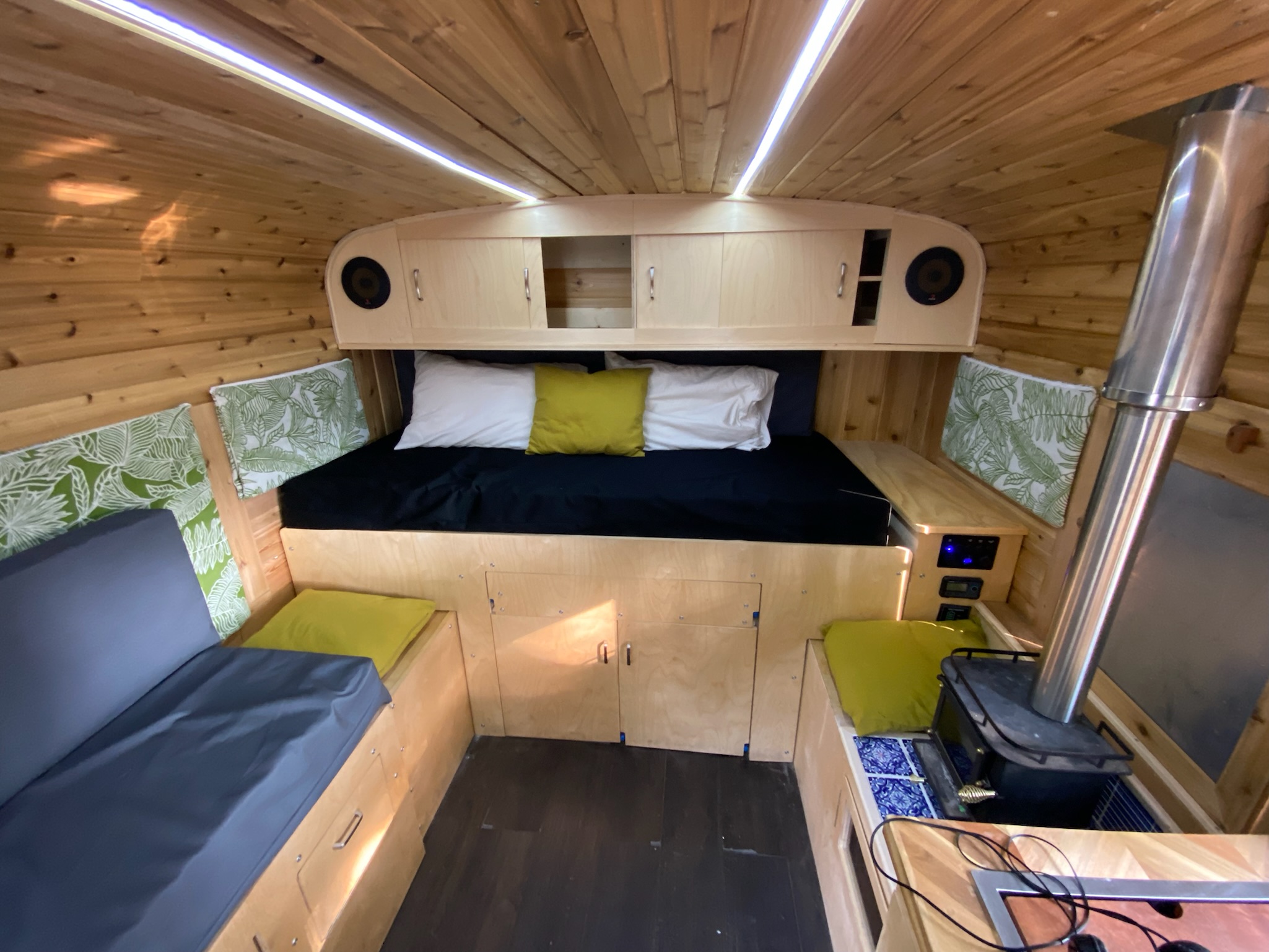 Explore this inviting rv rental: a cozy wood-paneled interior with a bed, seating, and a compact wood stove.. Chevrolet Chevrolet Express 1997