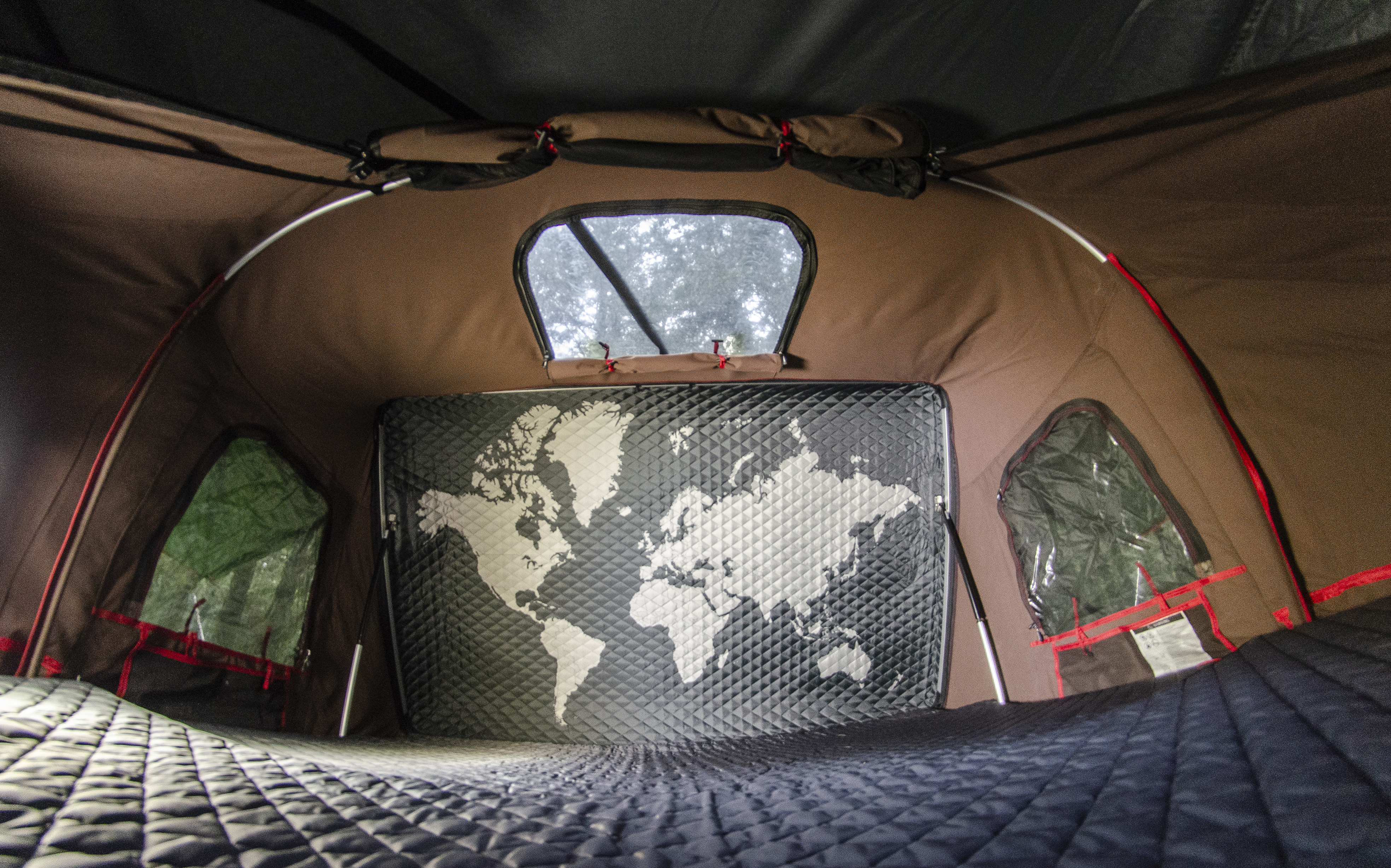 Inside an RV rental, showing a cozy tent interior with a quilted mattress, world map wall, and scenic windows, ready for adventure.. Volkswagen Vanagon 1989