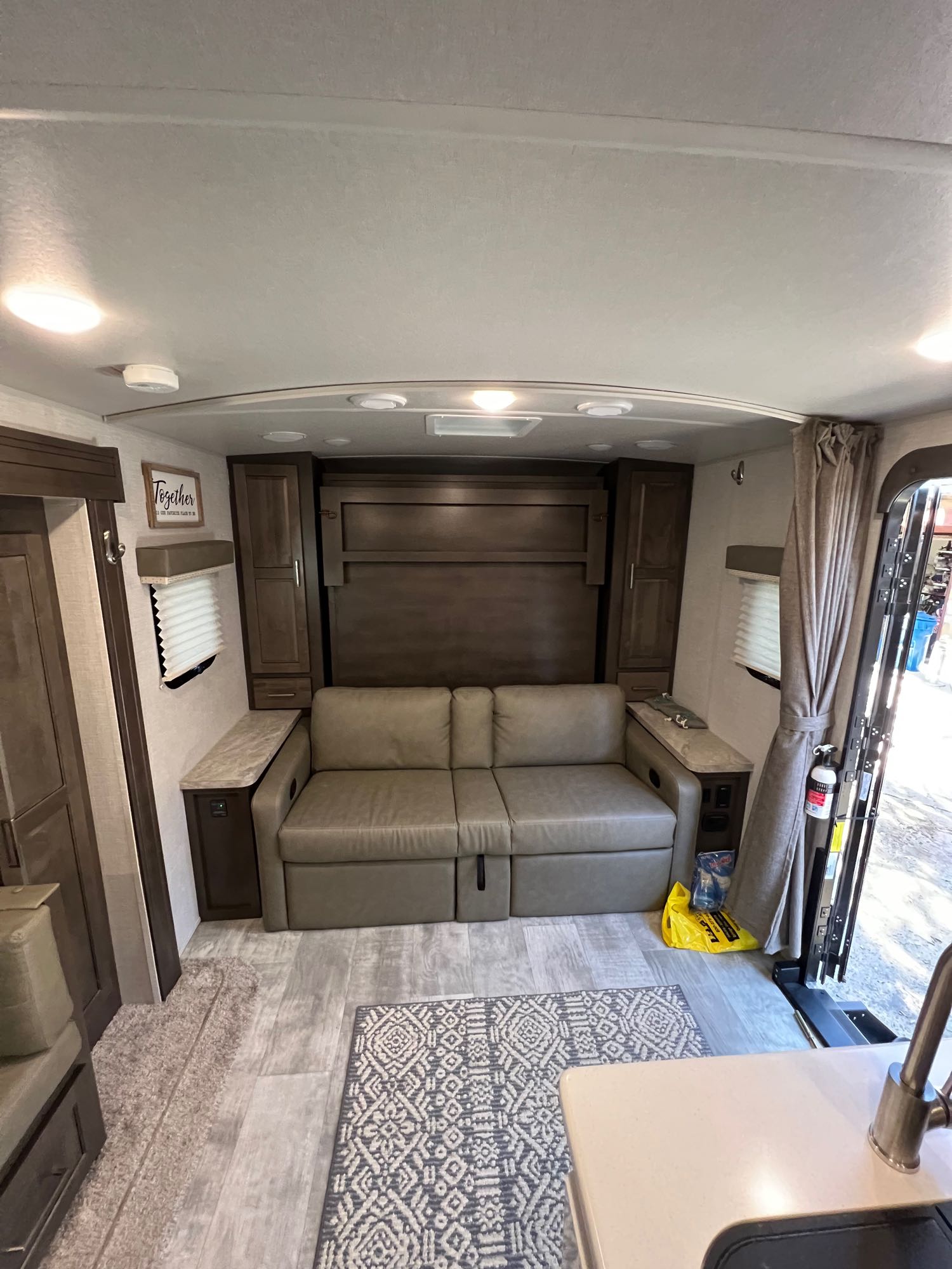 Inside an RV rental: a modern living space featuring a convertible sofa, murphy bed, and wood-look flooring for your travels.. Forest River Rockwood Mini Lite 2020