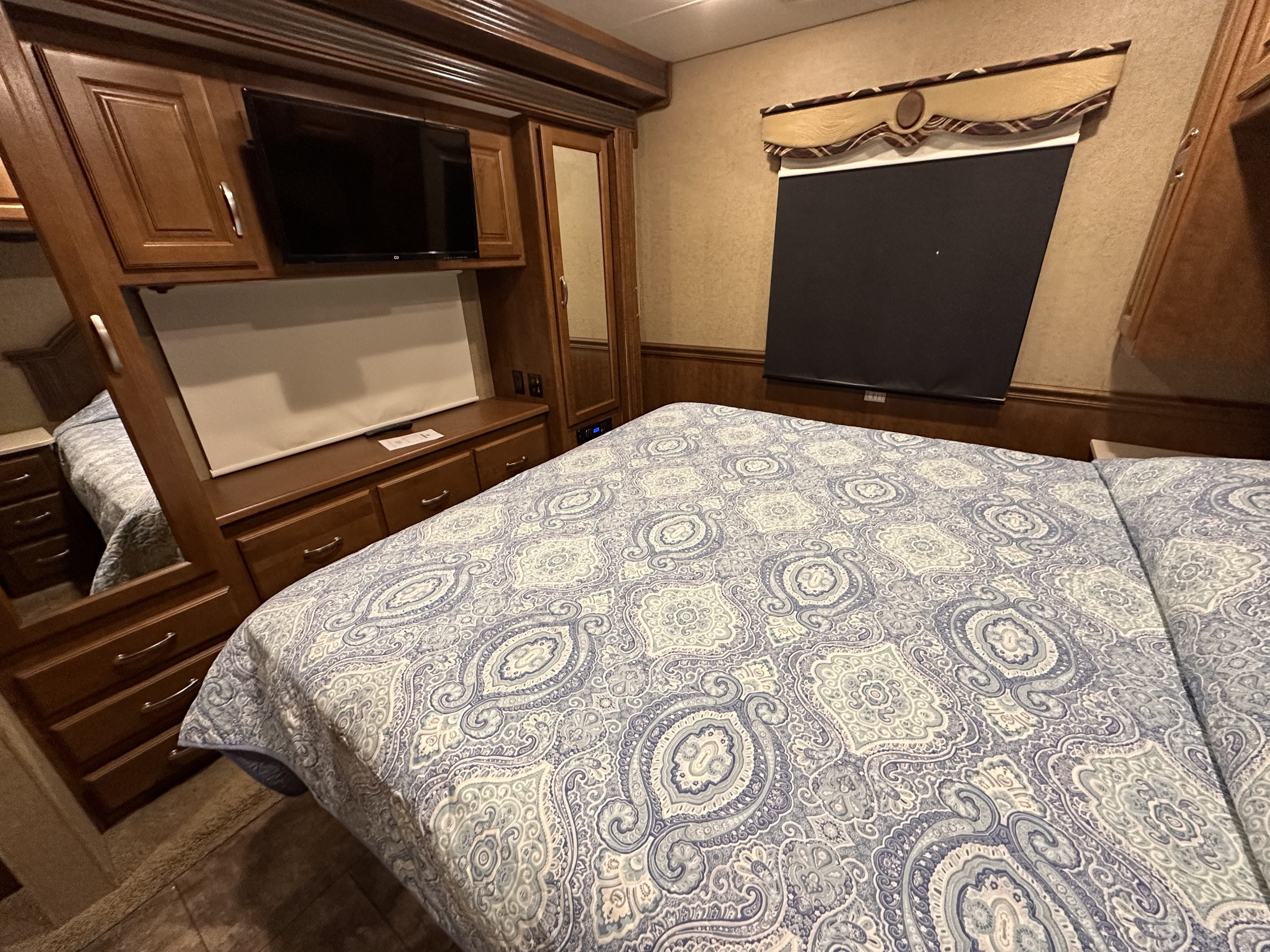 Experience comfort in this RV rental's bedroom interior, featuring a patterned bed, built-in storage, and a TV for a home-like stay.. Thor Challenger 2015