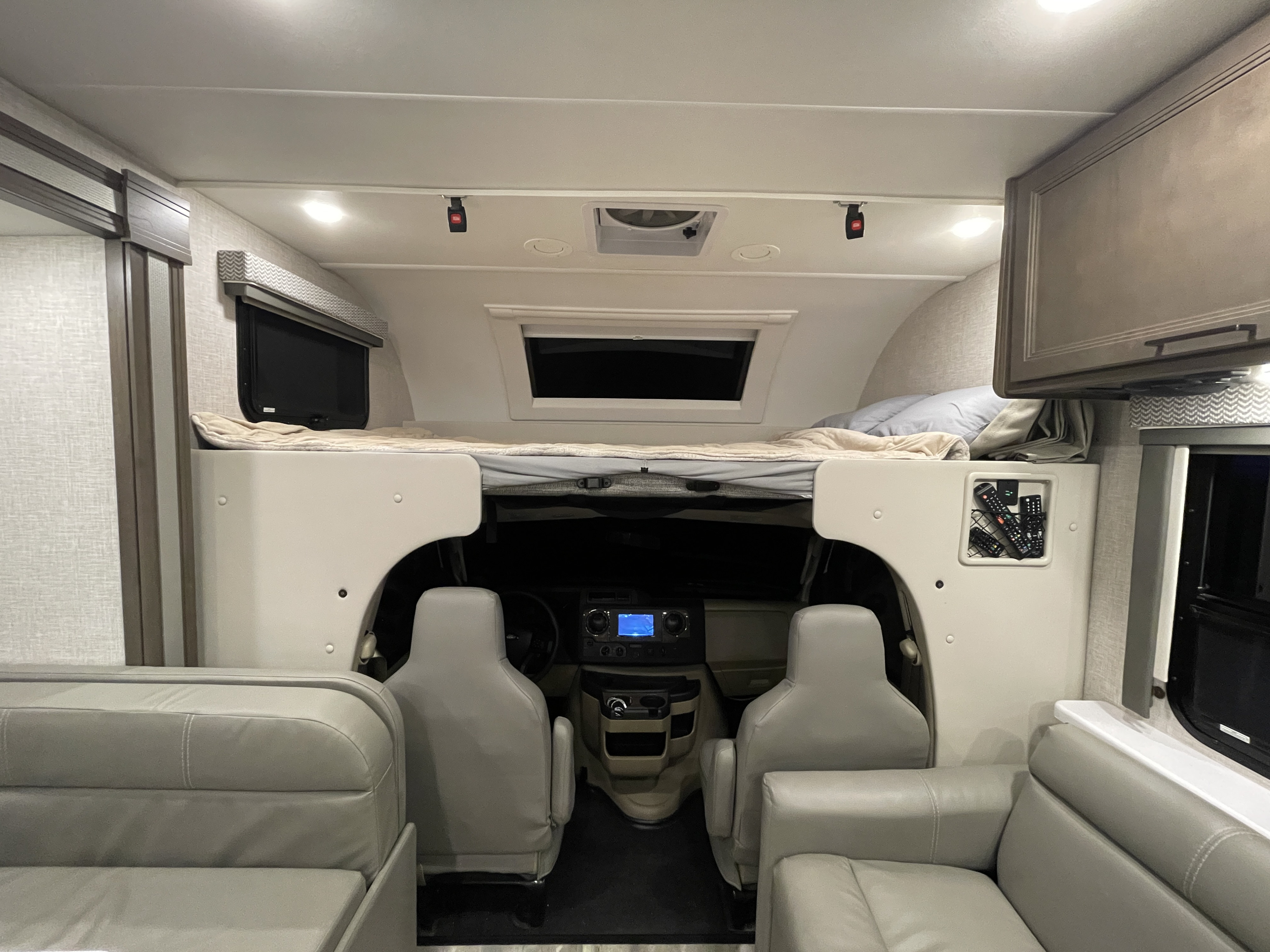 Cozy RV rental interior showing over-cab bunk, cockpit, and spacious seating areas for comfortable travels.. Thor Motor Coach Quantum 2023
