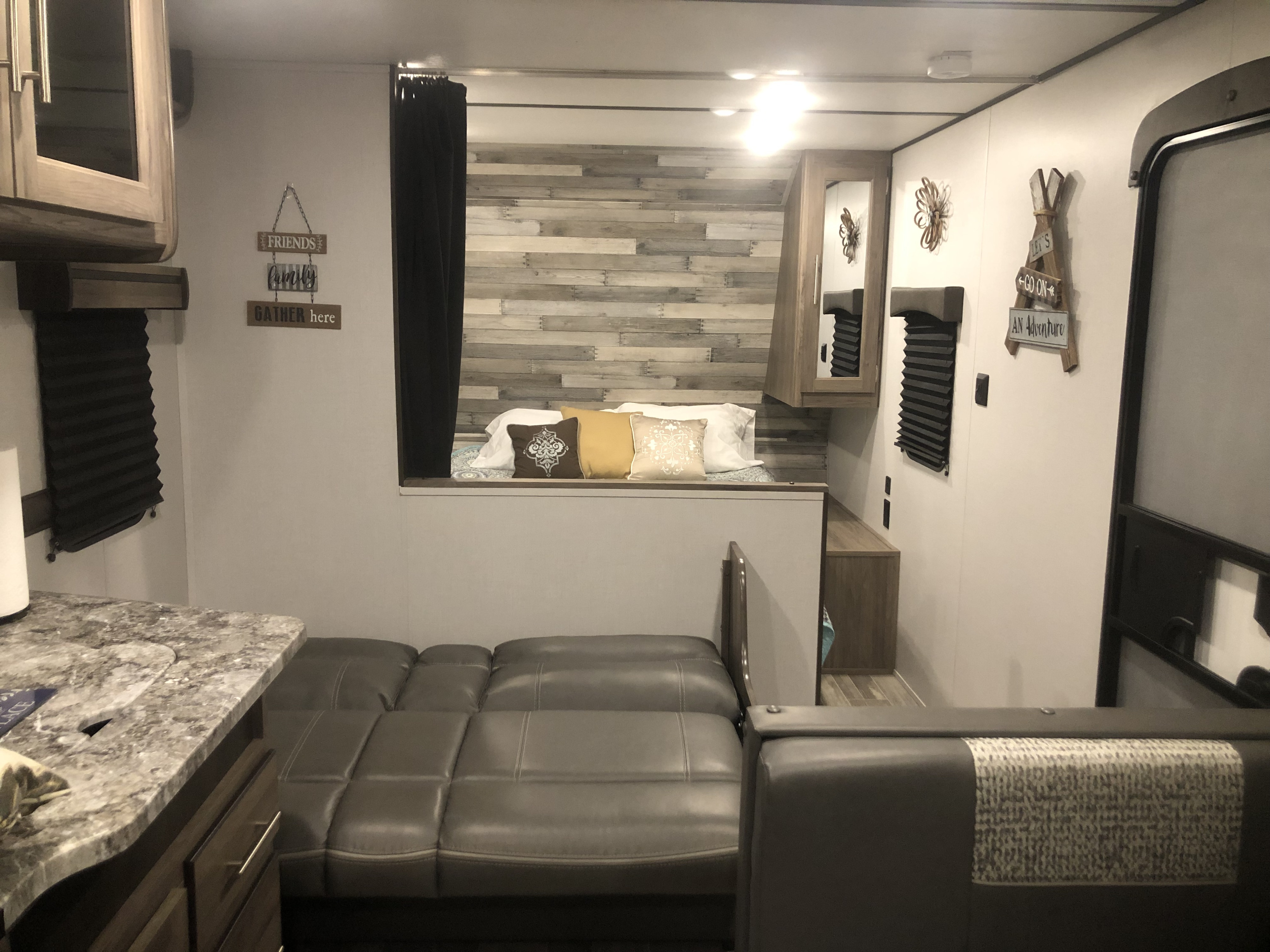 RV rental interior: A cozy living area with a convertible sofa, bed nook, and kitchen counter in a modern camper.. Crossroads RV Zinger Lite 2020