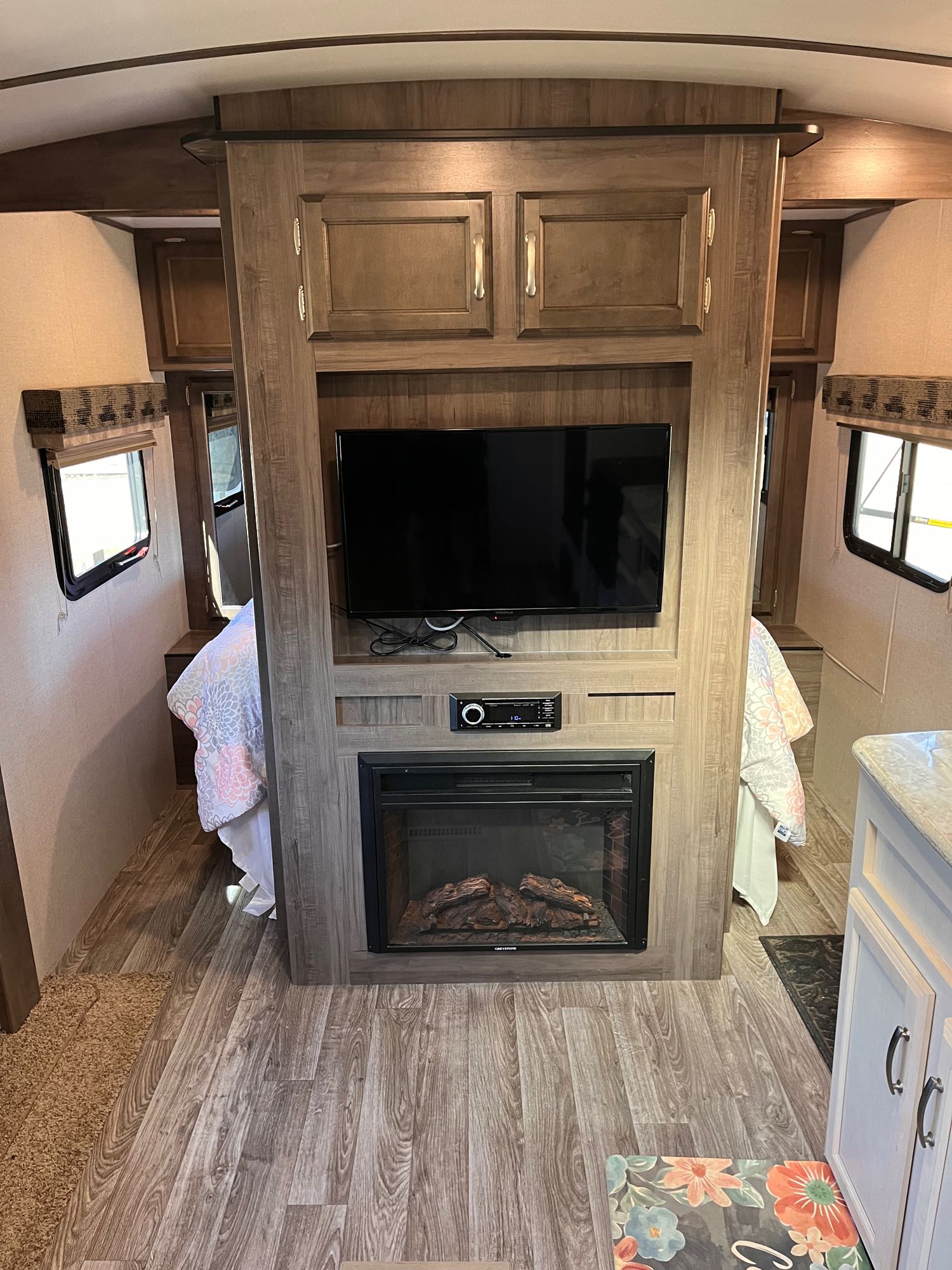 RV rental interior: cozy bedroom accessible from both sides of the central entertainment unit with TV & fireplace.. Minnie Minnie Plus 2019