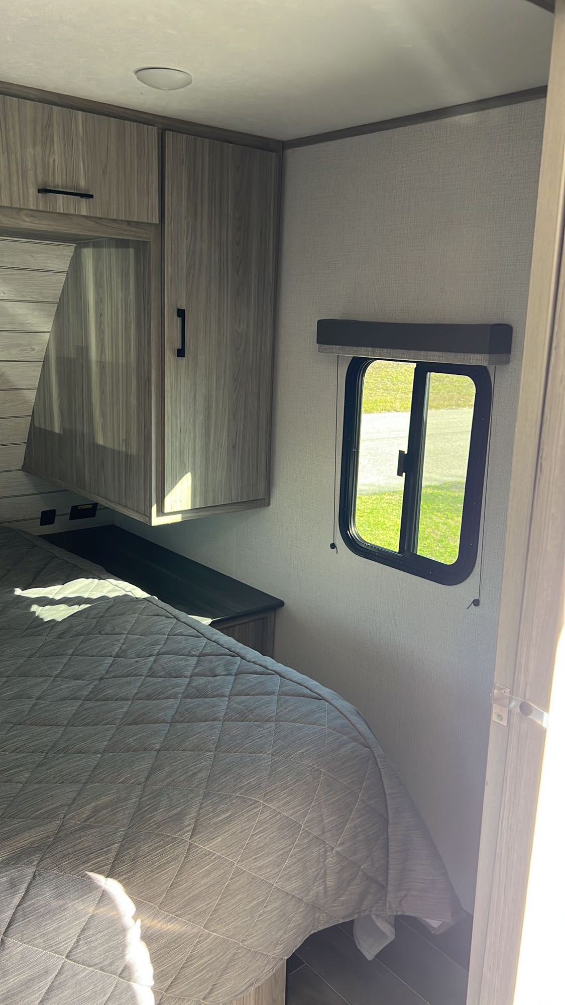 RV rental: Bedroom with quilted bed, wood cabinets, and window, offering a cozy retreat for your travels.. Keystone RV Passport SL 2022