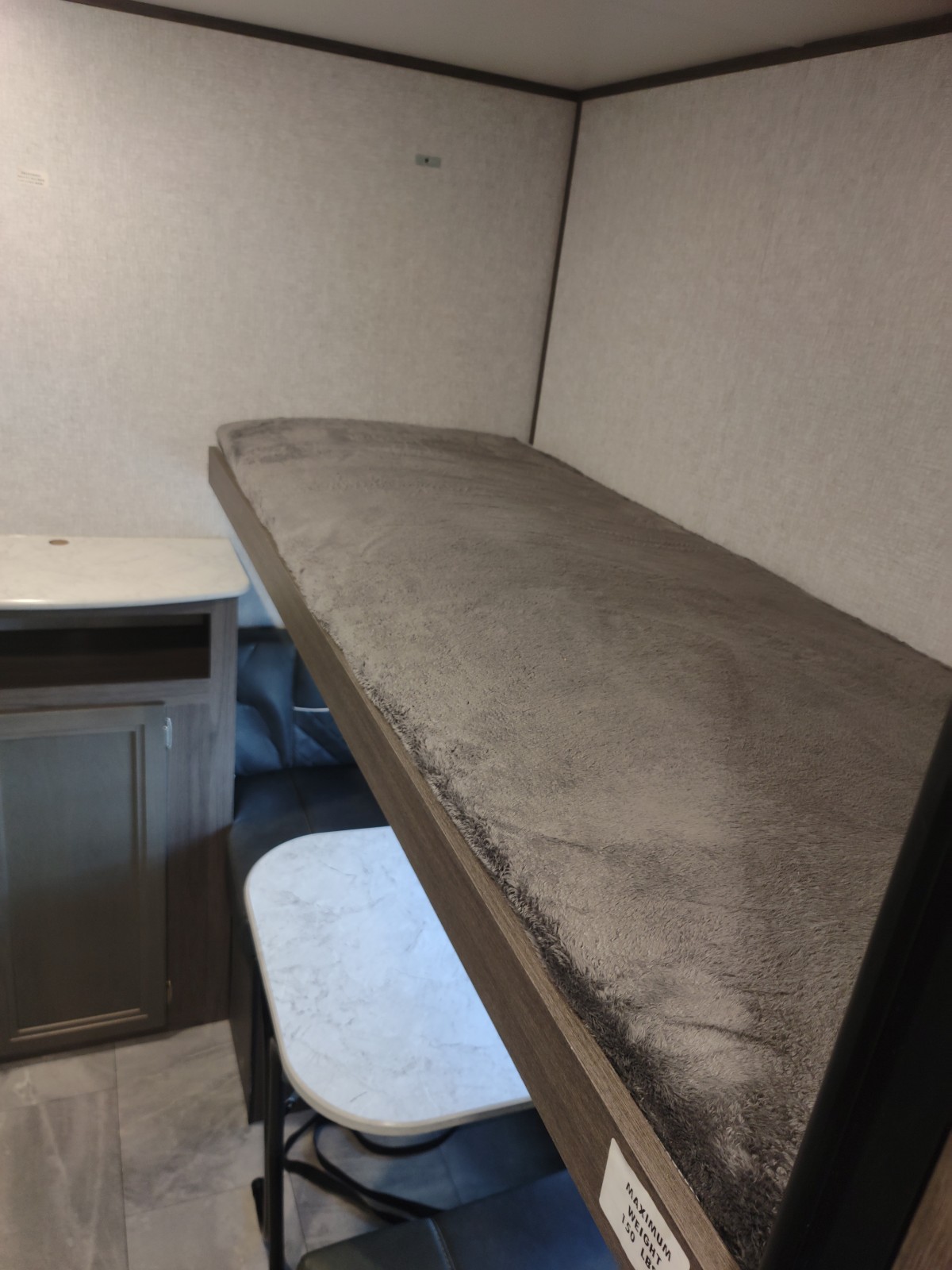 Explore this RV rental's cozy interior, featuring a plush bunk bed (150 lbs max) above a compact dinette area.. Dutchmen Kodiak SE 2021