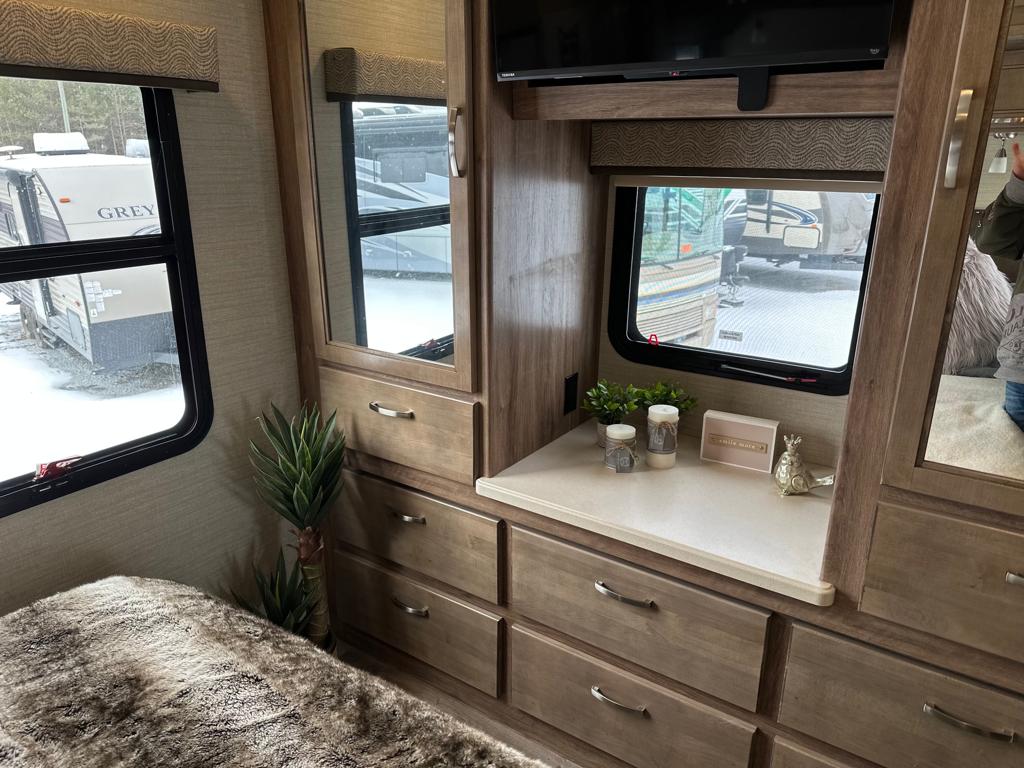 Experience RV rental comfort: a cozy bedroom setup with built-in storage, TV, and views of snowy landscape.. Jayco Precept 2019