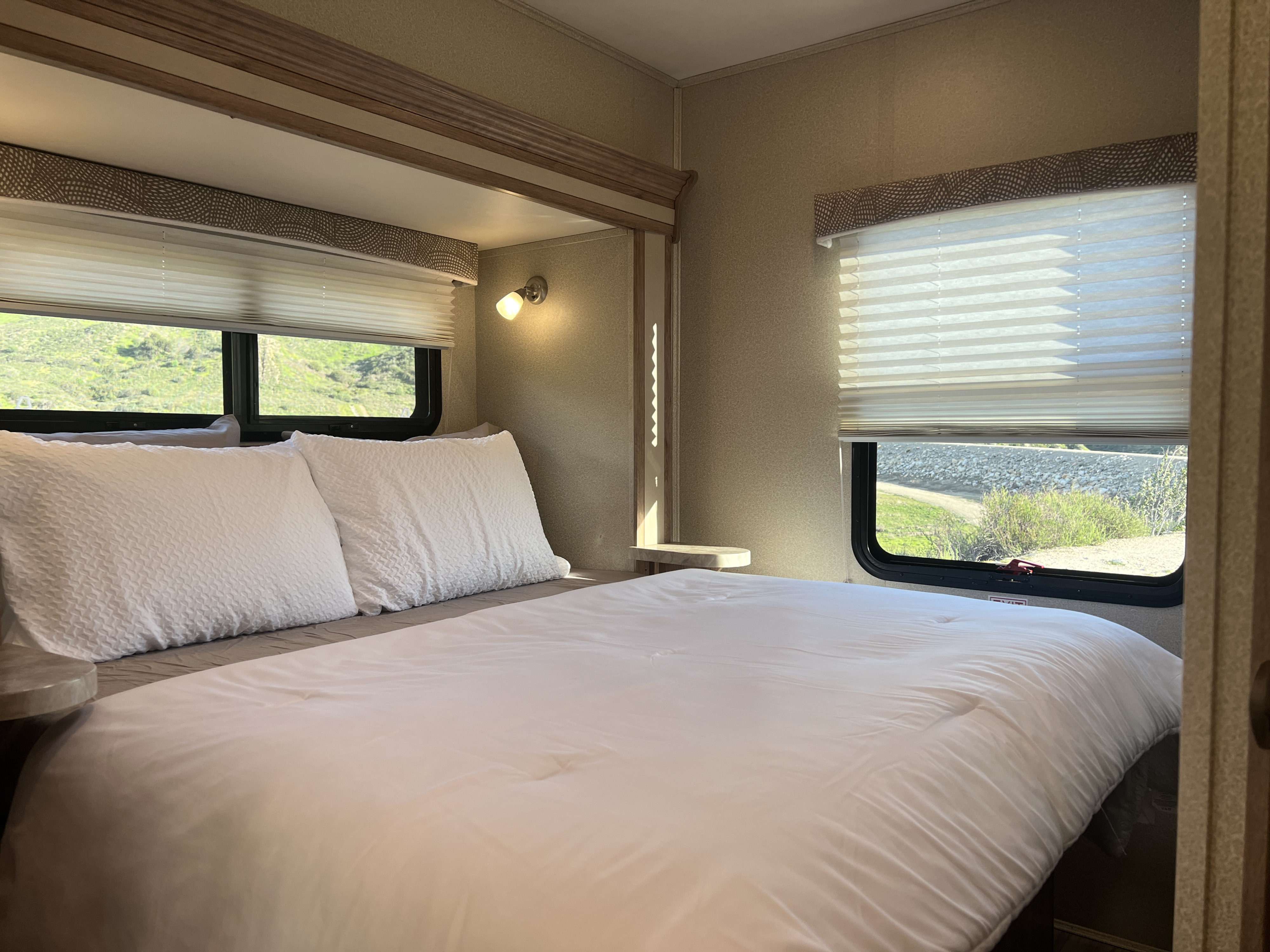 Main bedroom. Power slide-out. Short Queen with reading and floor lights and end tables on each side of bed. Bedding included in rental.. Entegra Coach Odyssey 2019