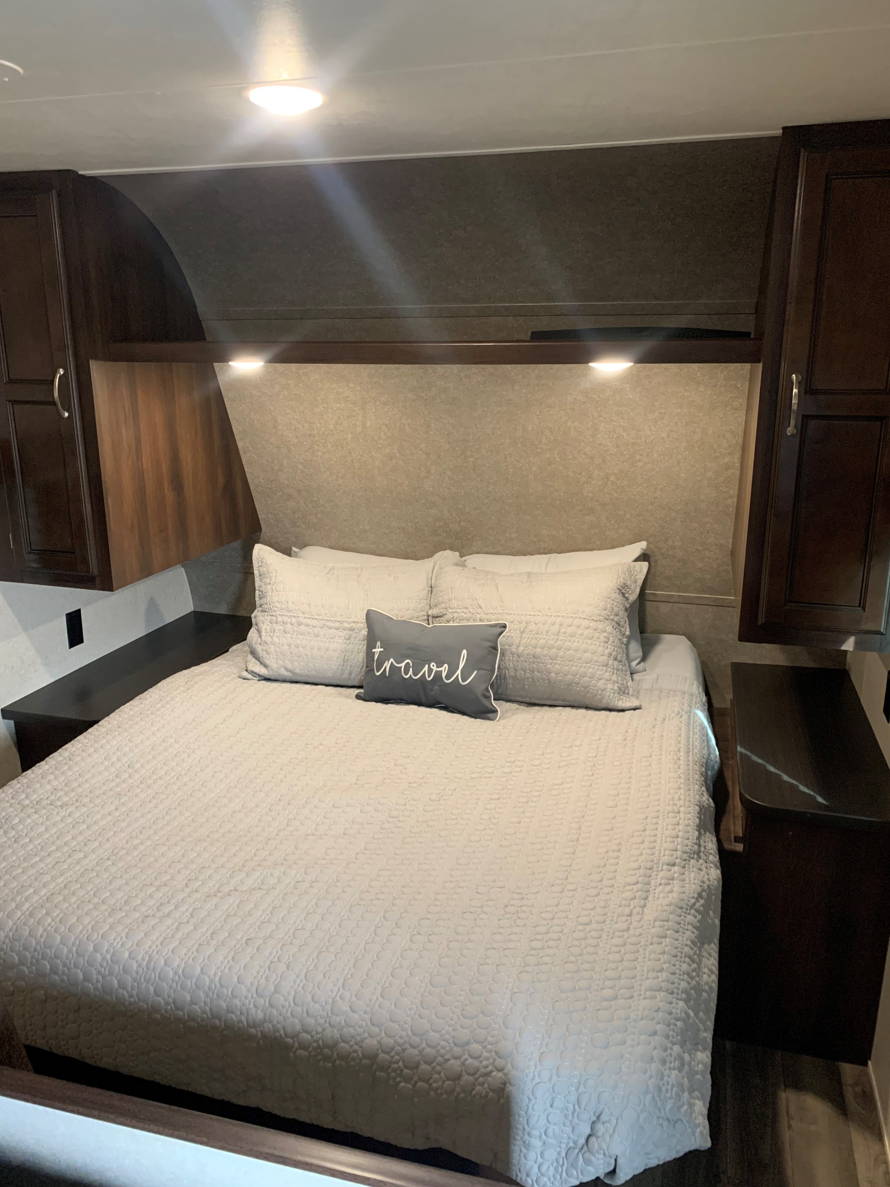 Cozy RV rental bedroom with a quilted bed, overhead cabinets, and soft reading lights, perfect for comfortable travel.. Jayco Jay Flight SLX 2018