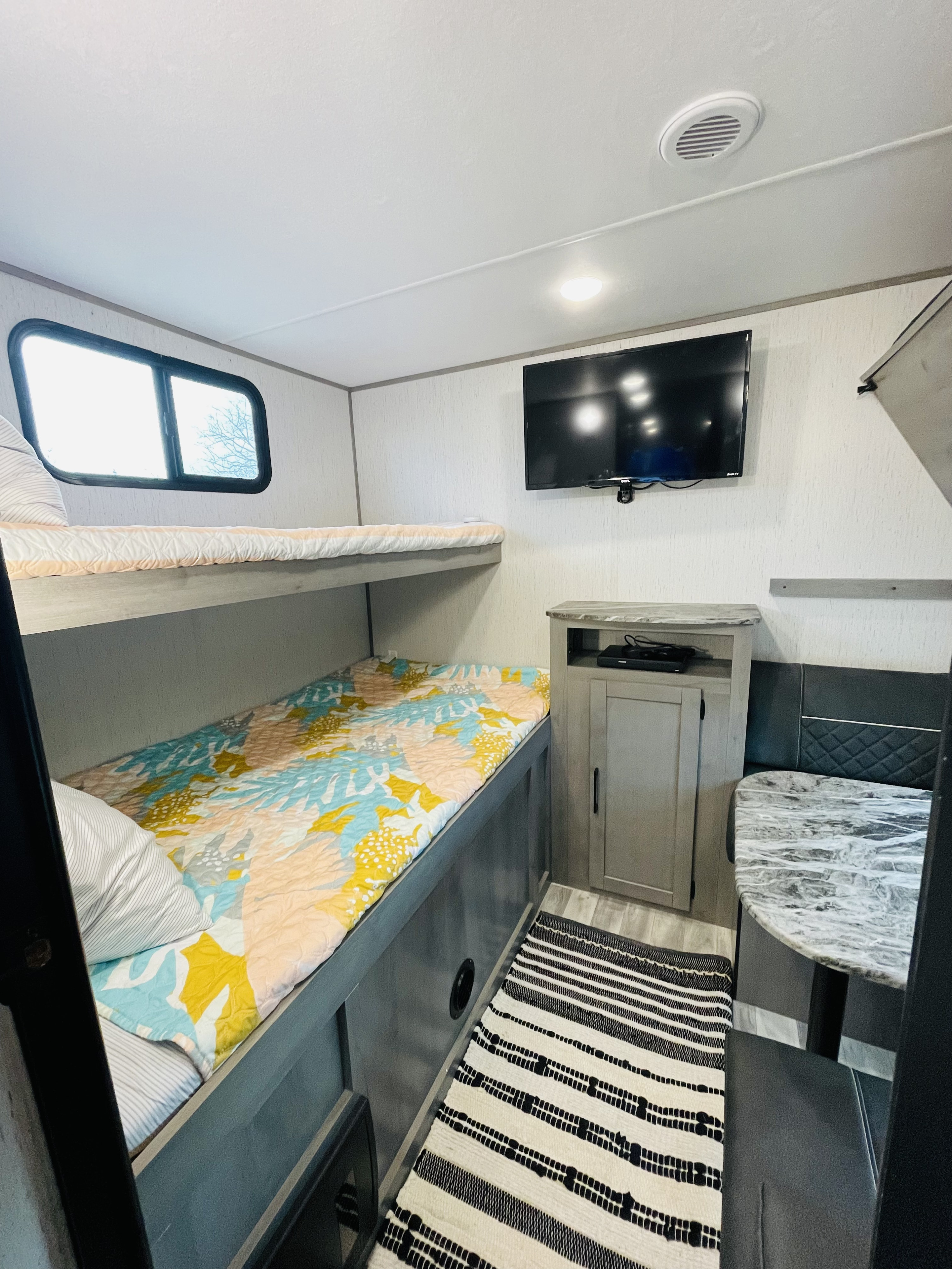 Cozy RV rental interior with colorful bunk beds, mounted TV, and dining area for comfortable travel.. Dutchmen Kodiak Ultra Lite 2021