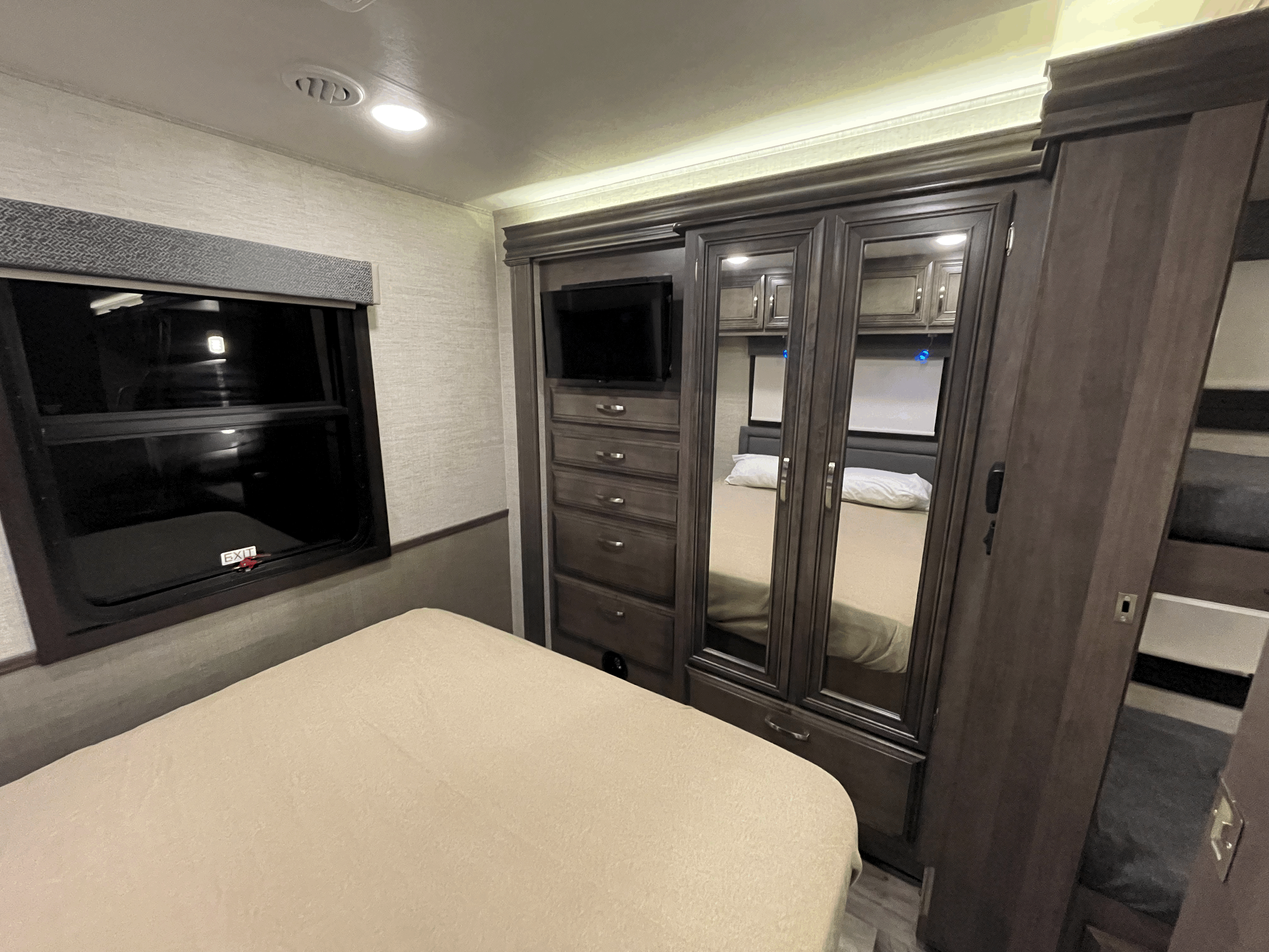 Spacious RV rental bedroom featuring a comfortable bed, mirrored wardrobe, dresser with TV, and bunk beds.. Jayco Alante 29F 2023