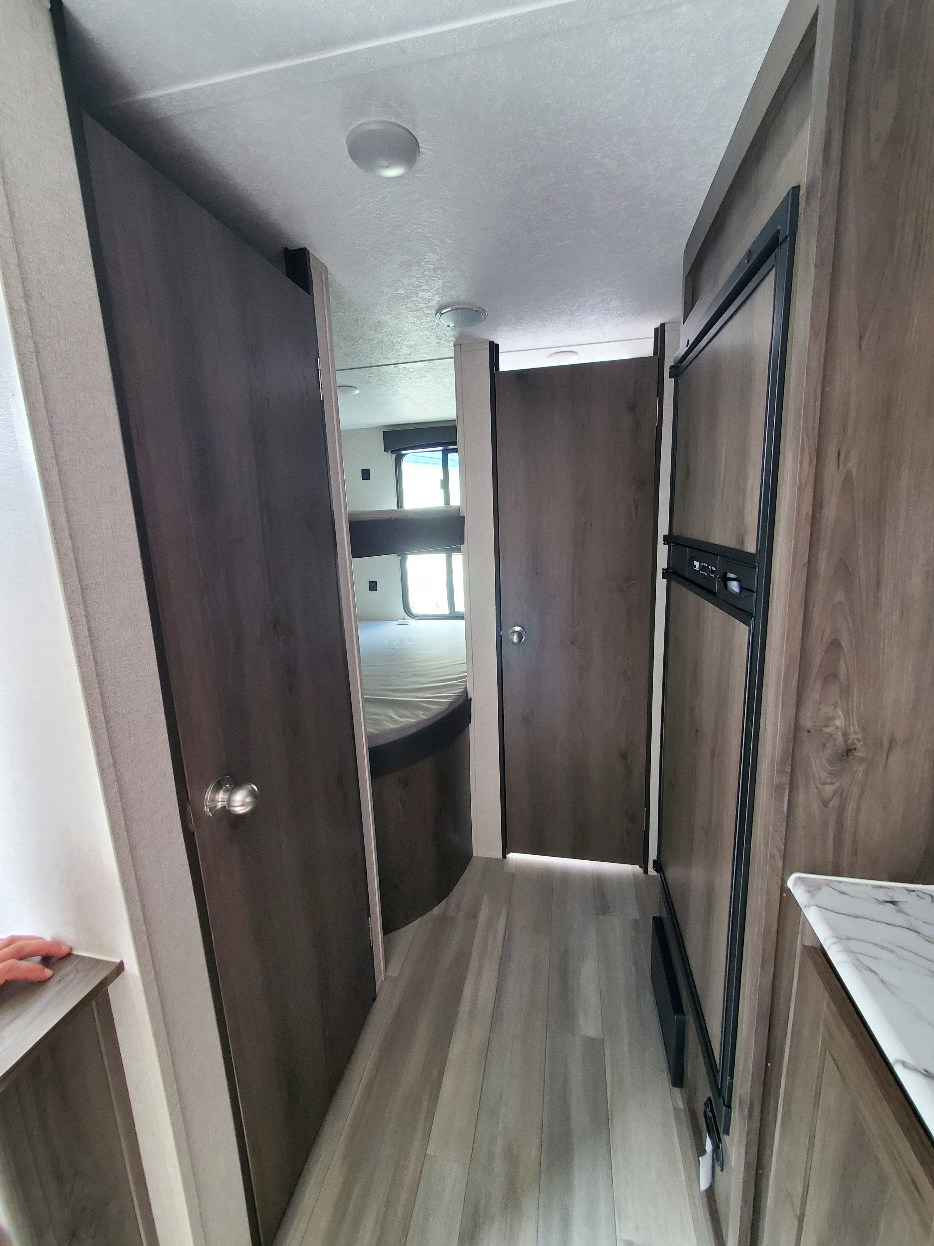 RV rental interior: Hallway with bunk beds visible through an open door on the left, and a refrigerator on the right.. Coachmen Clipper 82DBU 2021