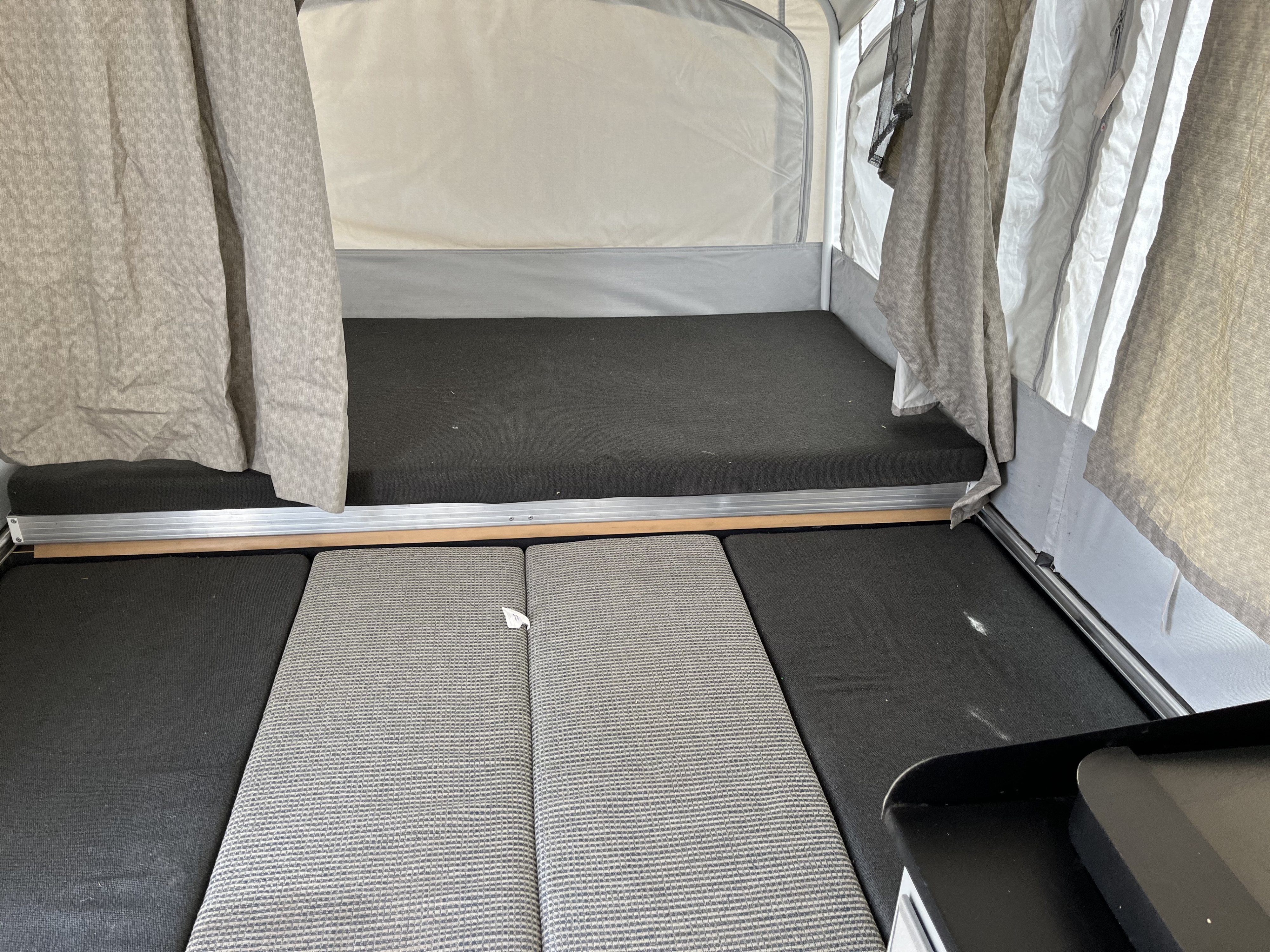 RV rental pop-up camper interior: raised sleeping area with dark grey mattress and floor cushions for comfort.. Fleetwood Cobalt 2008