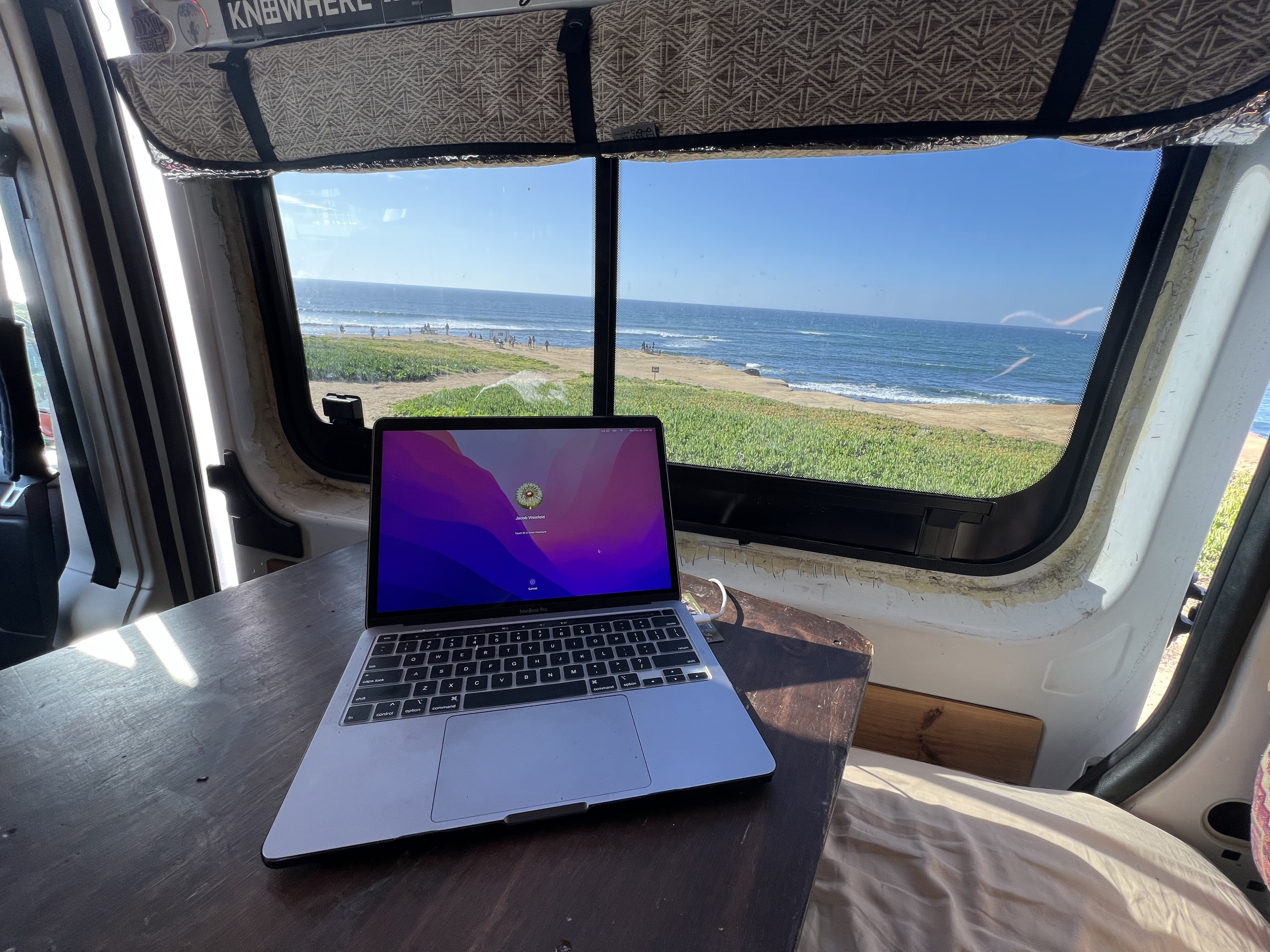 Remote work from an RV rental: a laptop on a table with a stunning beach and ocean view, people enjoying the sun.. Dodge Ram Promaster 2500 2017