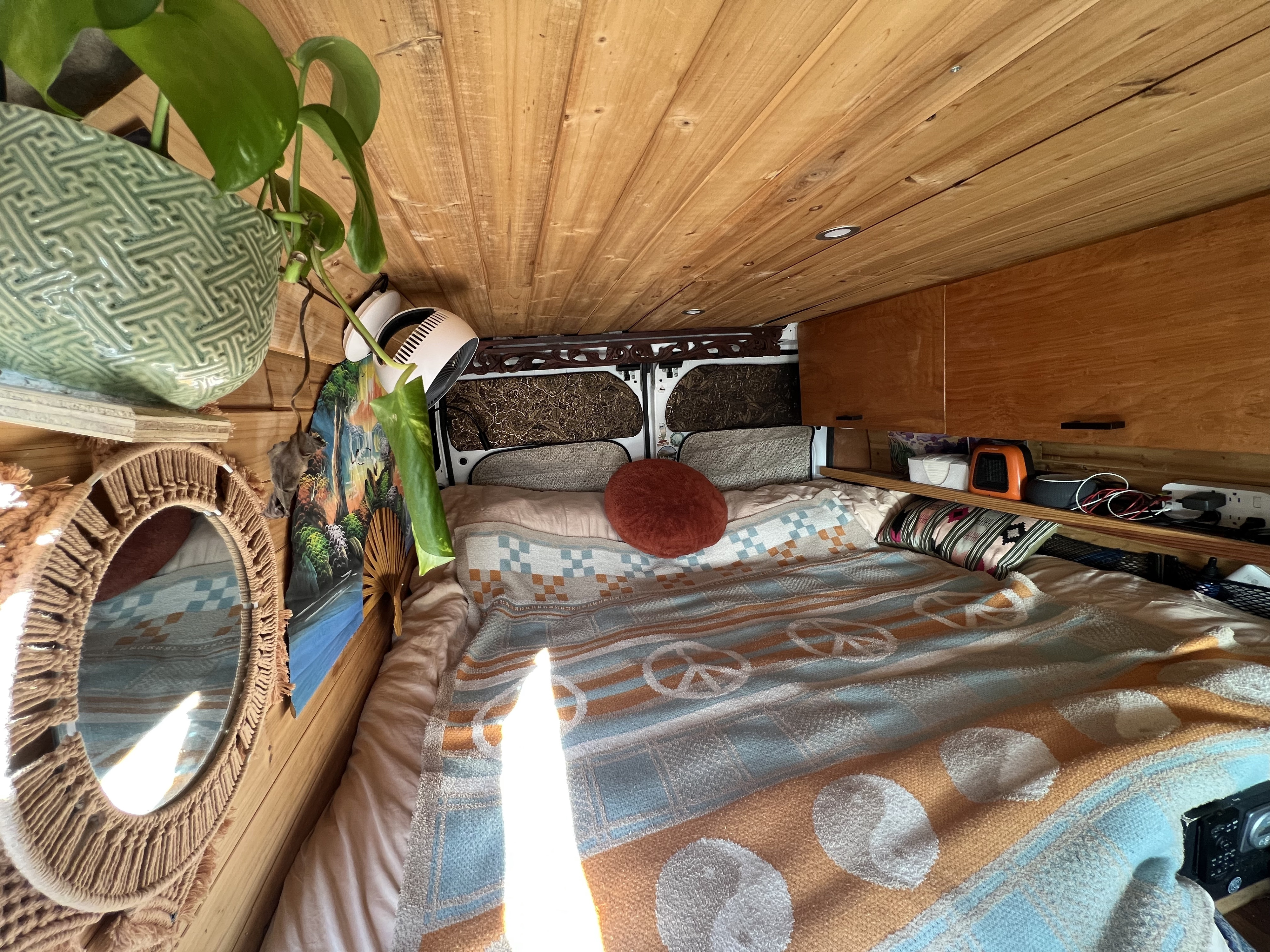 Step inside this cozy rv rental! Features a comfy bed with a peace sign blanket, warm wooden walls, and functional storage.. Dodge Ram Promaster 2500 2017