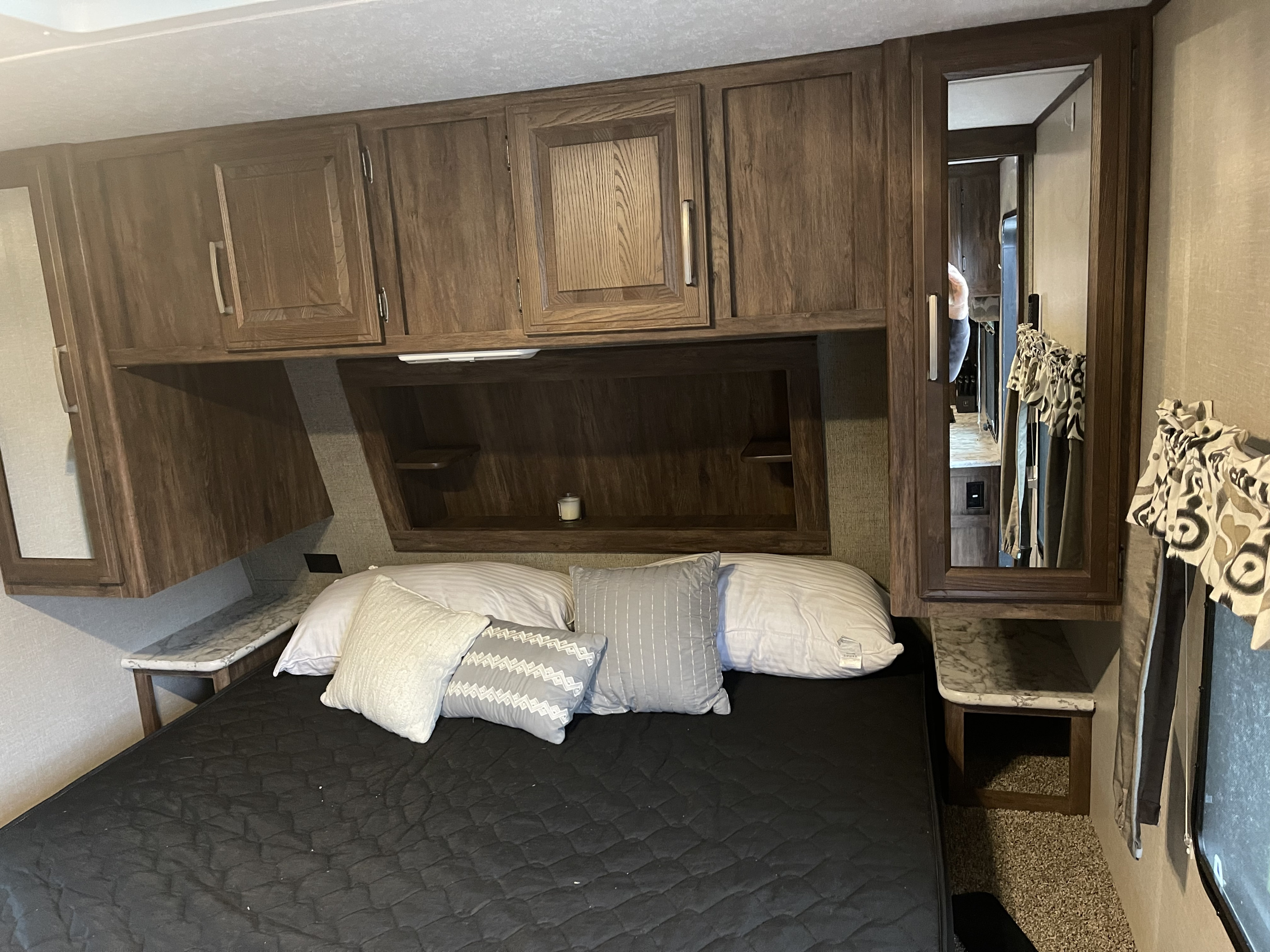 RV rental bedroom interior, showing a bed, wooden cabinets, and mirrored wardrobe for guests.. Keystone RV Cougar 2017