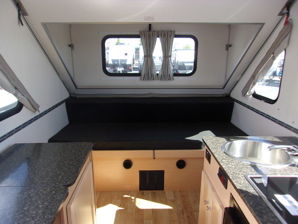 Explore this compact RV rental's interior! Features a comfortable sleeping area, kitchenette with sink/stove, and pop-up design.. A Liner Expedition 2022