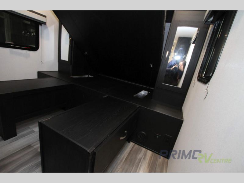 RV rental bedroom: Dark-toned interior with a lifted storage bed, revealing hidden compartments, drawers & power outlets.. Coachmen Freedom Express 252RBS 2022