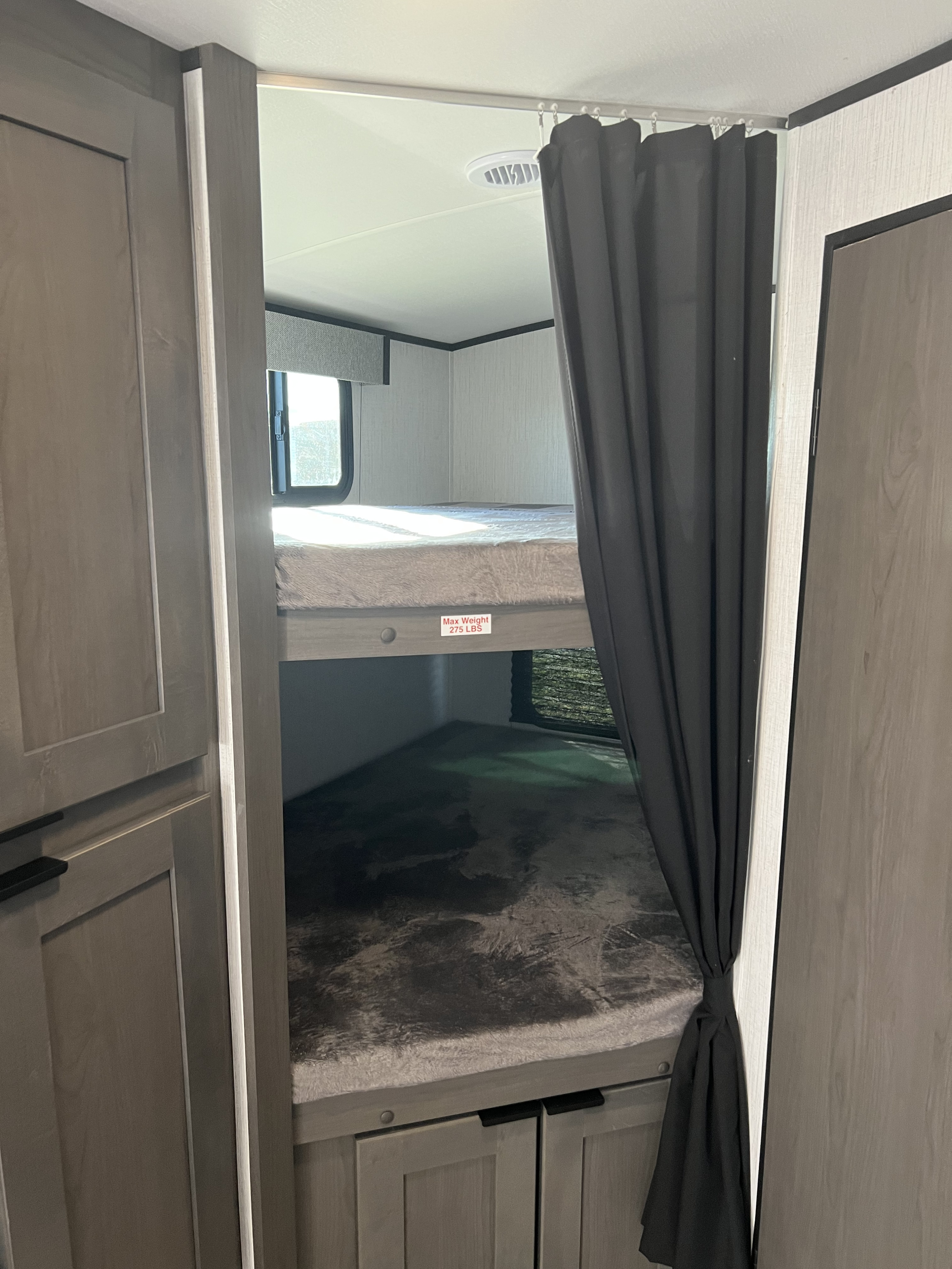 Inside an **RV rental**, showing a bunk bed area with a privacy curtain. The top bunk has a 'Max Weight 275 LBS' sticker.. Cruiser RV MPG Ultra Lite 2022