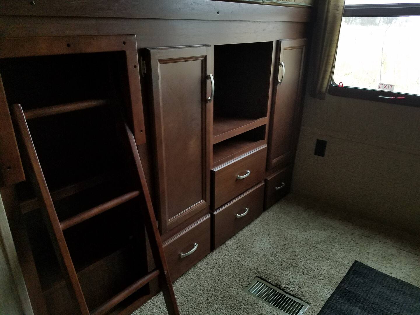 RV rental interior: Wooden bunk beds with ladder, storage cabinets, drawers, and window. Carpeted floor.. Keystone Outback 2016