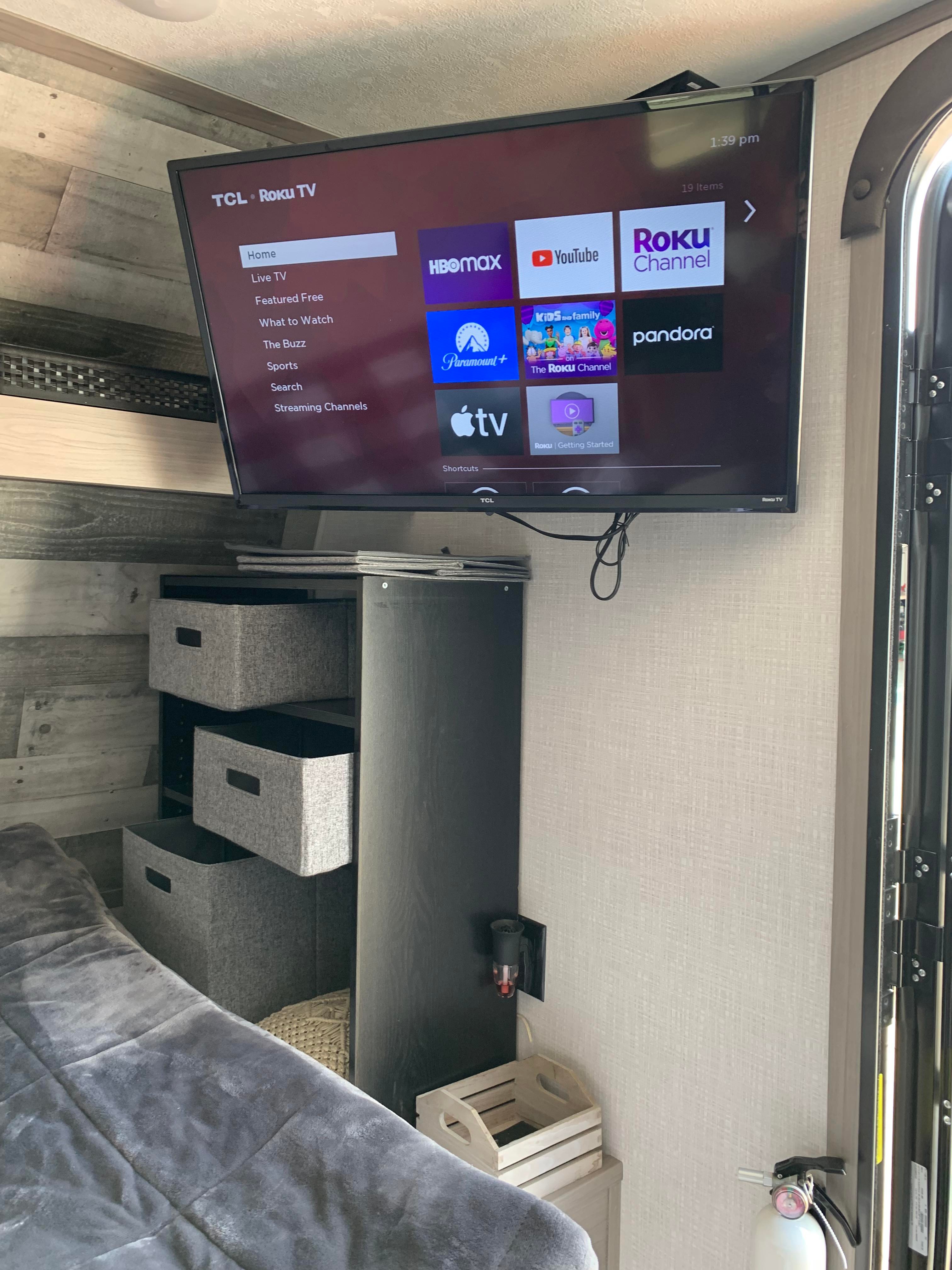 RV rental interior featuring a TCL Roku TV with streaming apps, cozy bed, and practical storage. Ideal for travel entertainment.. Dutchmen Coleman Lantern LT 2023