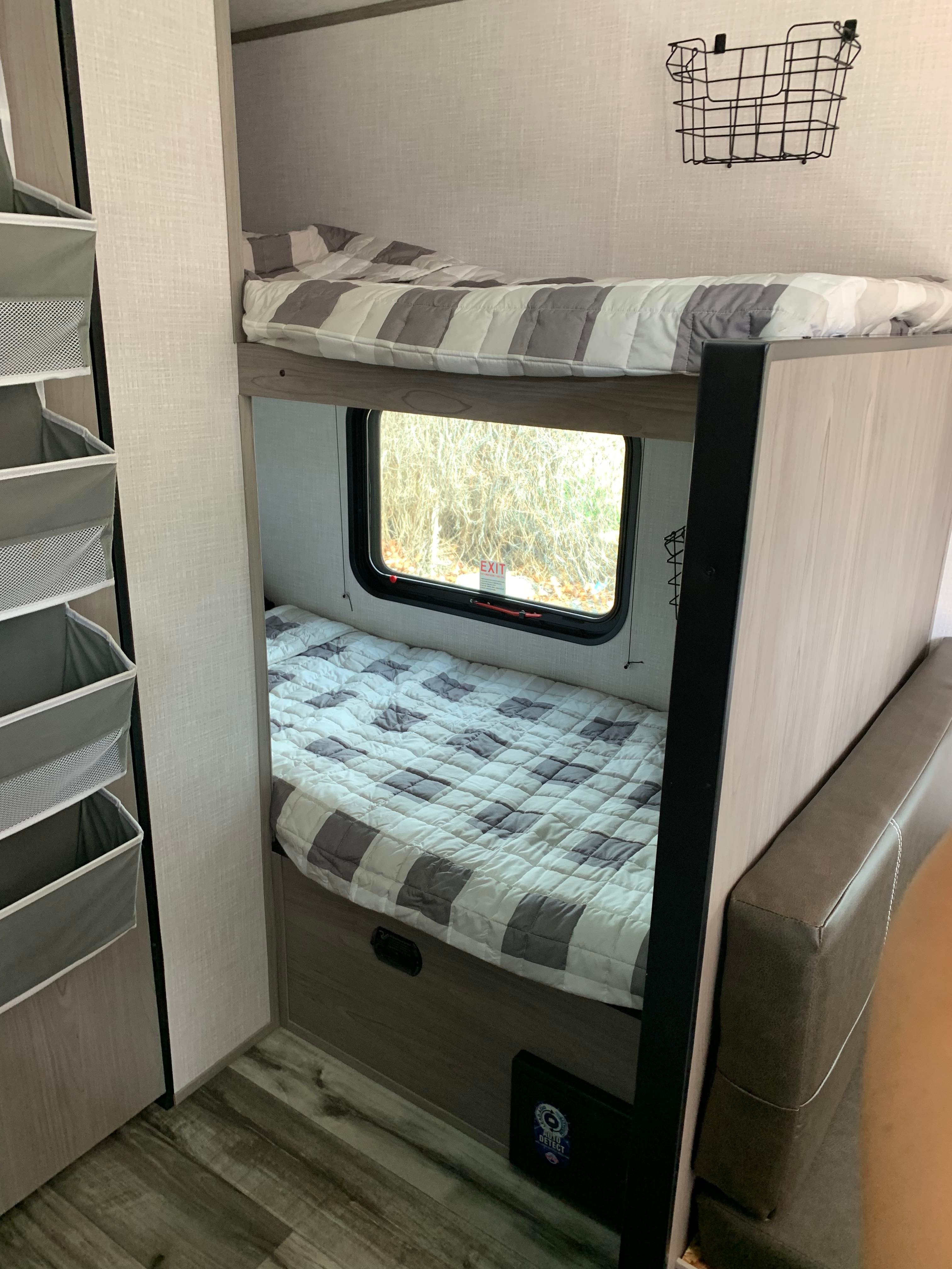 Inside an RV rental: comfortable bunk beds for extra sleeping space. Includes window views, smart storage, and seating.. Dutchmen Coleman Lantern LT 2023