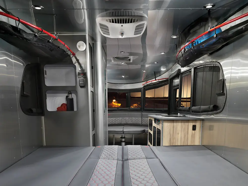 Spacious RV rental interior featuring a comfortable bed, dinette, kitchen, and large scenic windows. Ideal for travel adventures.. Airstream Basecamp 2022